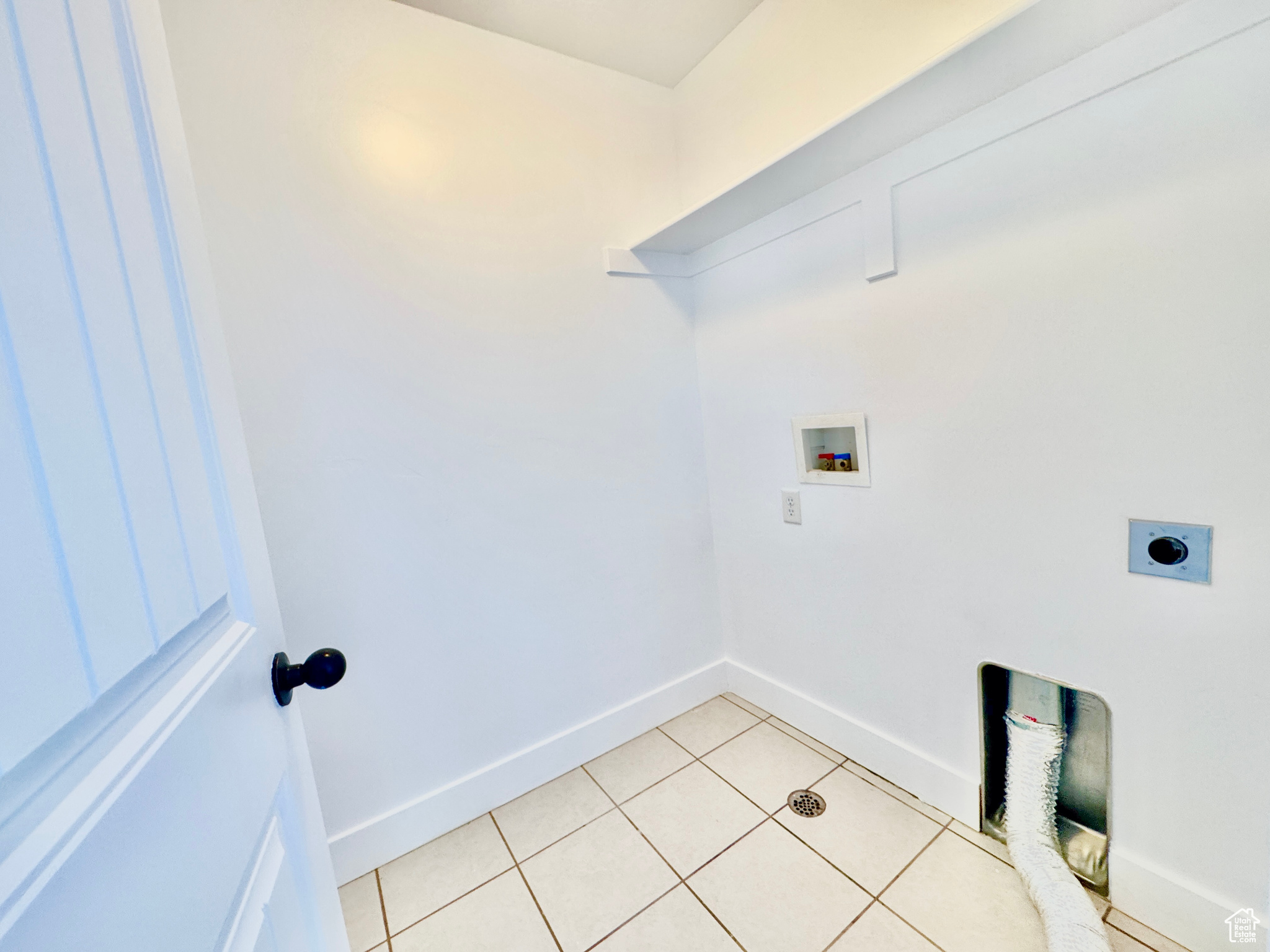 Washroom with electric dryer hookup, light tile patterned floors, and washer hookup