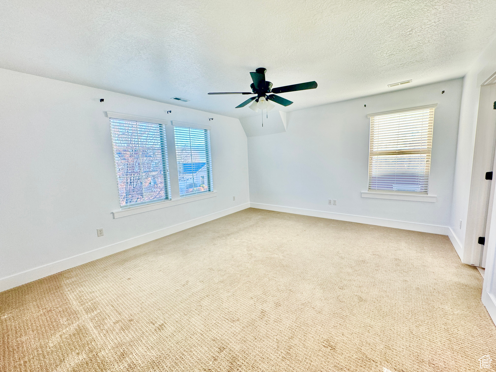 Carpeted spare room featuring a textured ceiling and ceiling fan