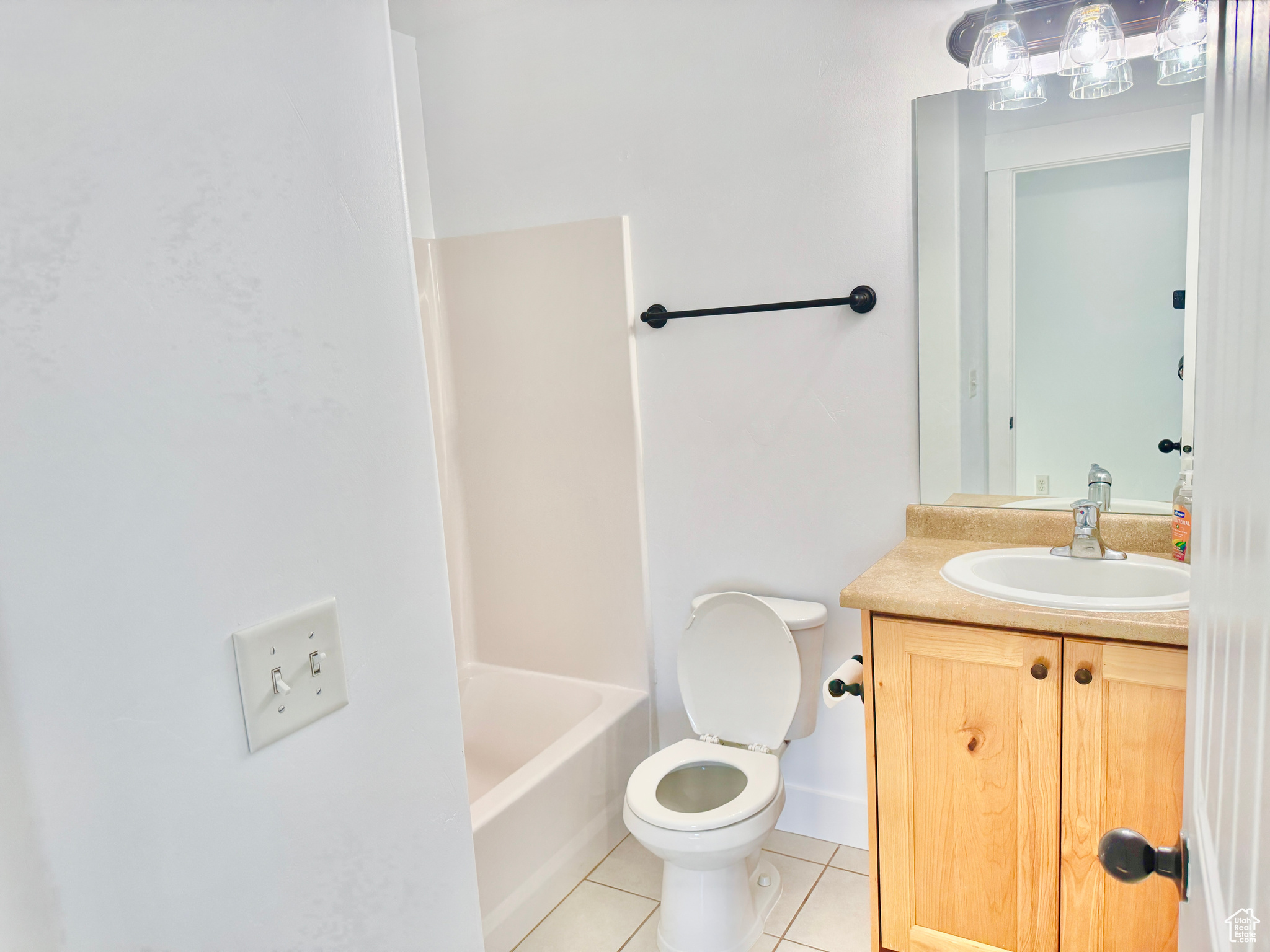 Full bathroom with tile patterned floors, washtub / shower combination, vanity, and toilet