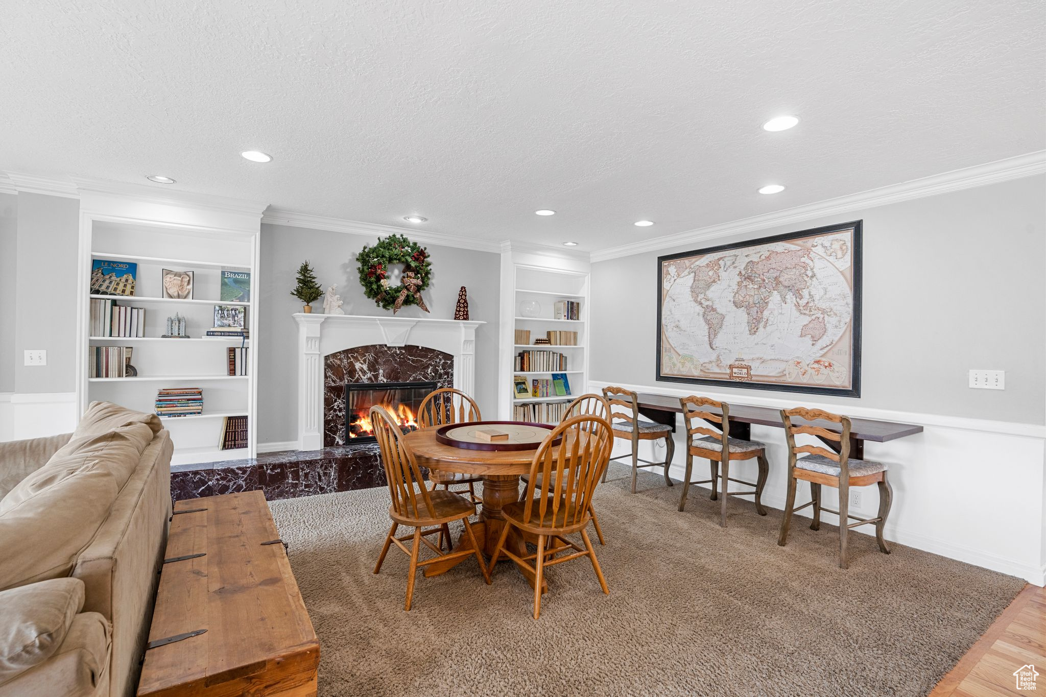 Dining /Family Room area with built in shelves, a textured ceiling, crown molding, wood-type flooring, and a premium fireplace