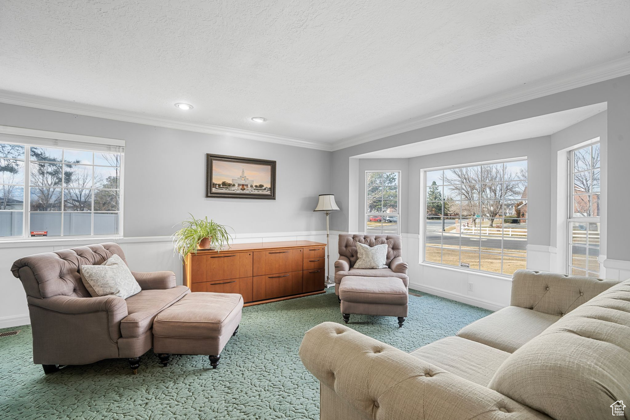 Living room featuring a wealth of natural light, carpet, a textured ceiling, and ornamental molding