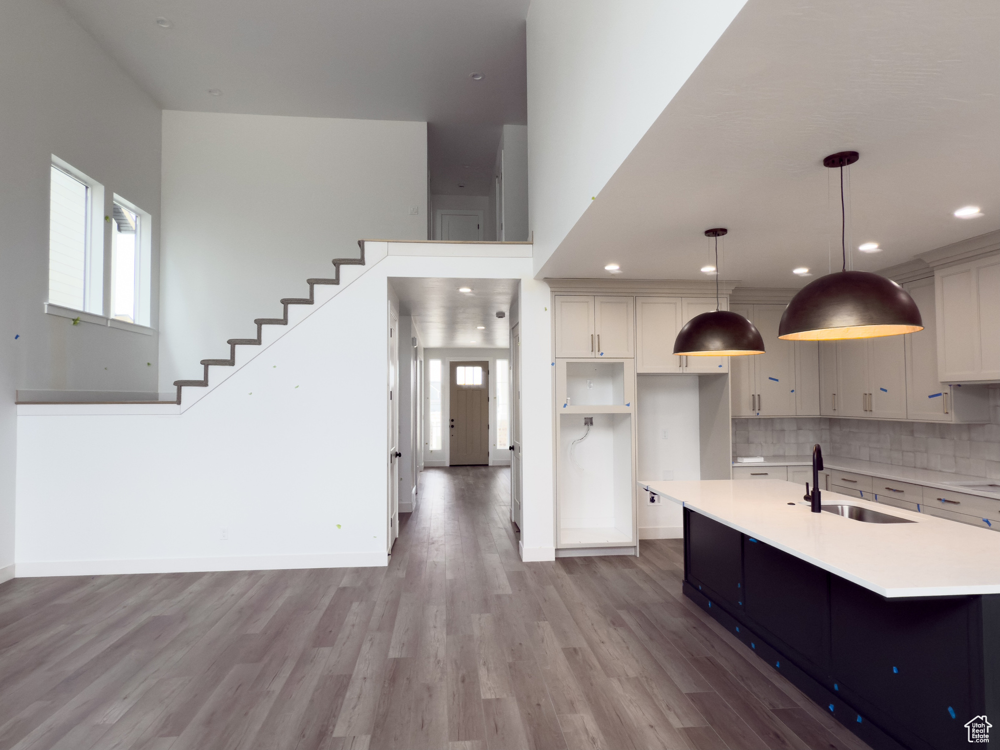 Kitchen with sink, hanging light fixtures, tasteful backsplash, light hardwood / wood-style flooring, and a center island with sink