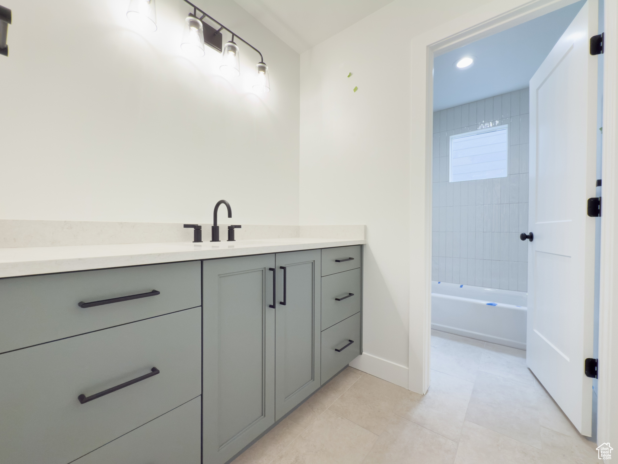 Bathroom featuring tile patterned floors, vanity, and tiled shower / bath combo