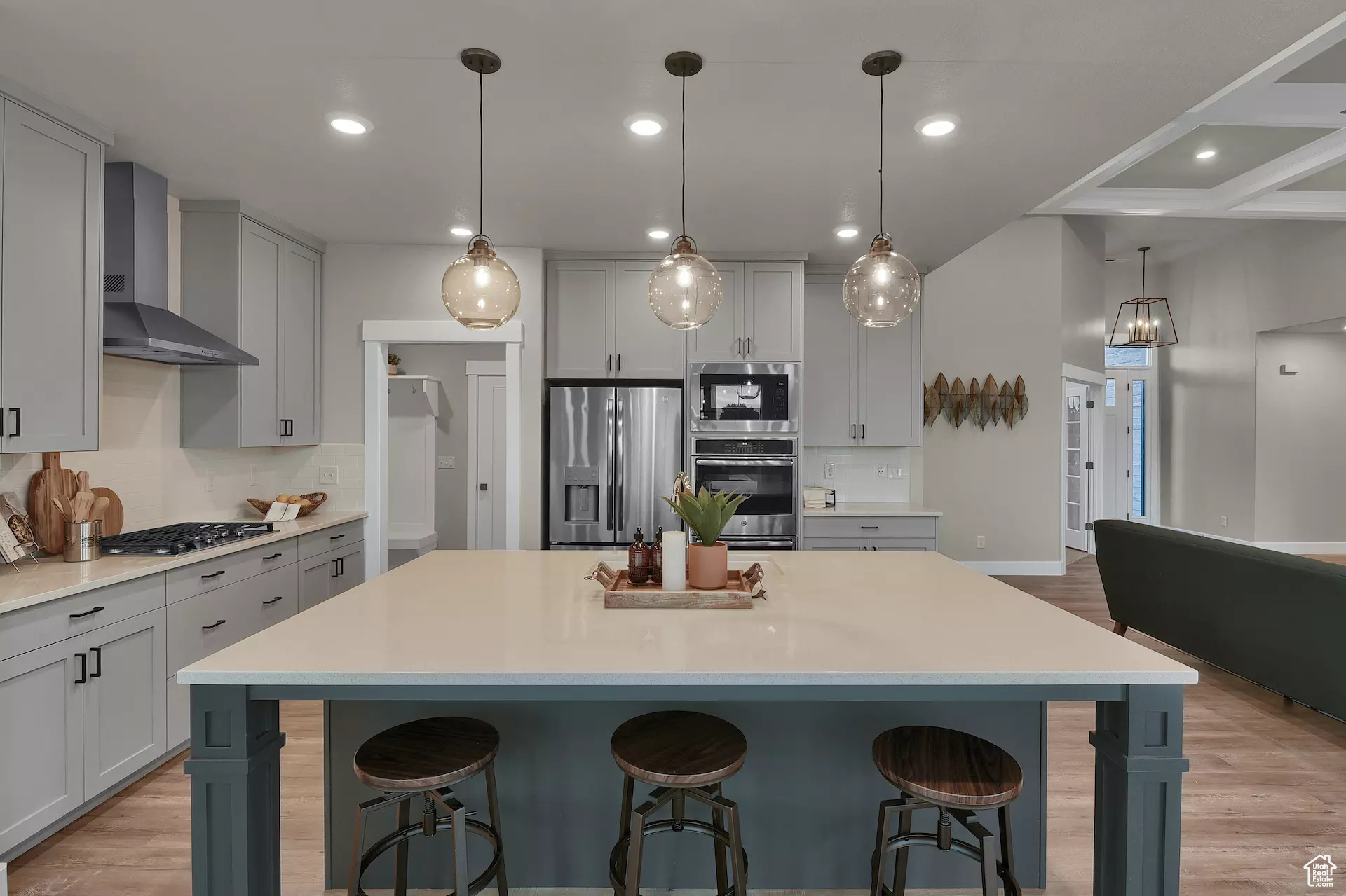 Kitchen with pendant lighting, wall chimney exhaust hood, a large island, a kitchen bar, and stainless steel appliances