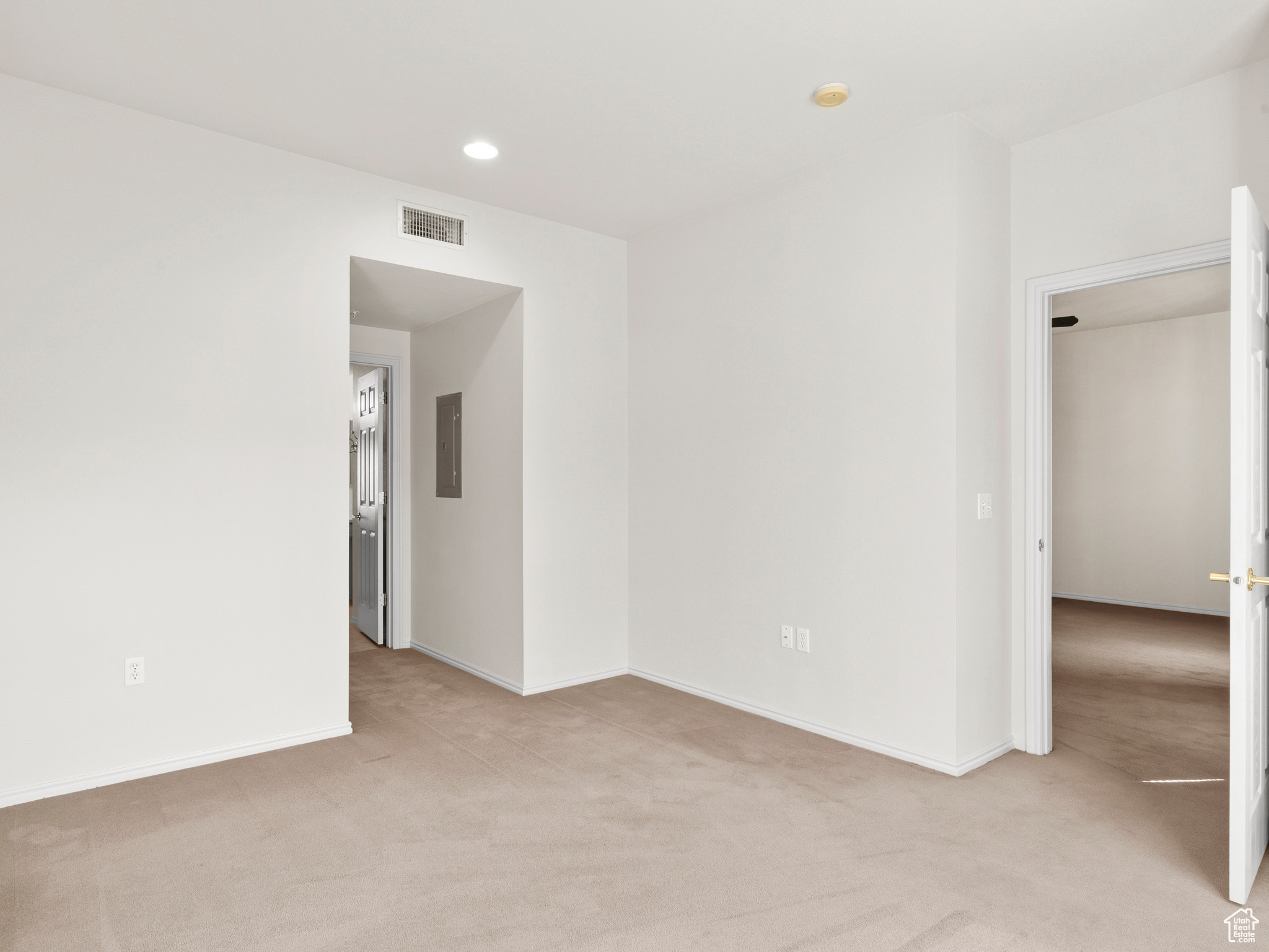 Carpeted spare room featuring electric panel