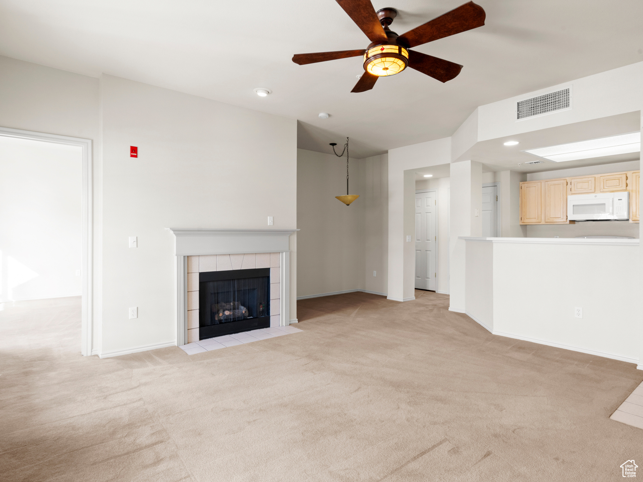 Unfurnished living room featuring ceiling fan, a fireplace, and light carpet