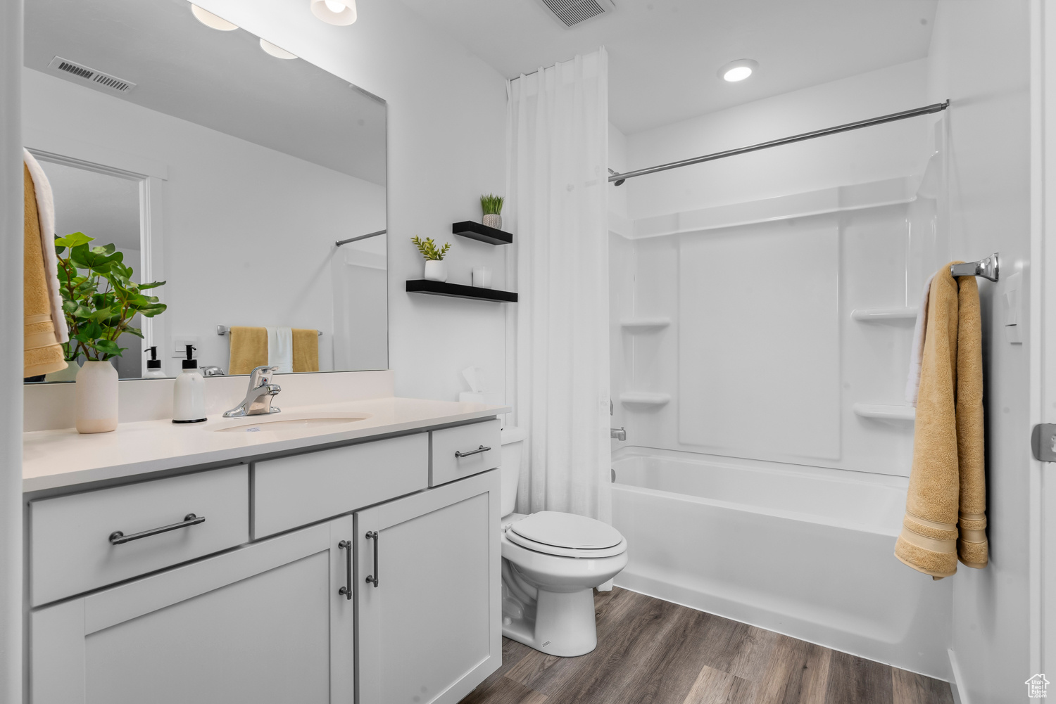 Full bathroom featuring shower / tub combo with curtain, vanity, wood-type flooring, and toilet