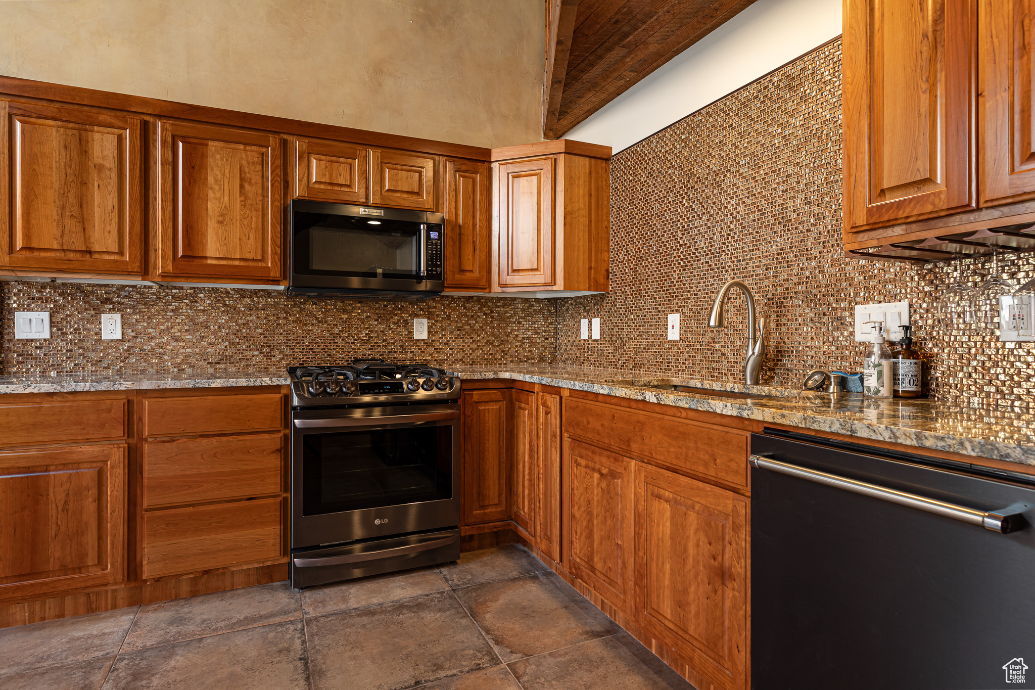 Kitchen featuring tasteful backsplash, light stone countertops, sink, and stainless steel appliances