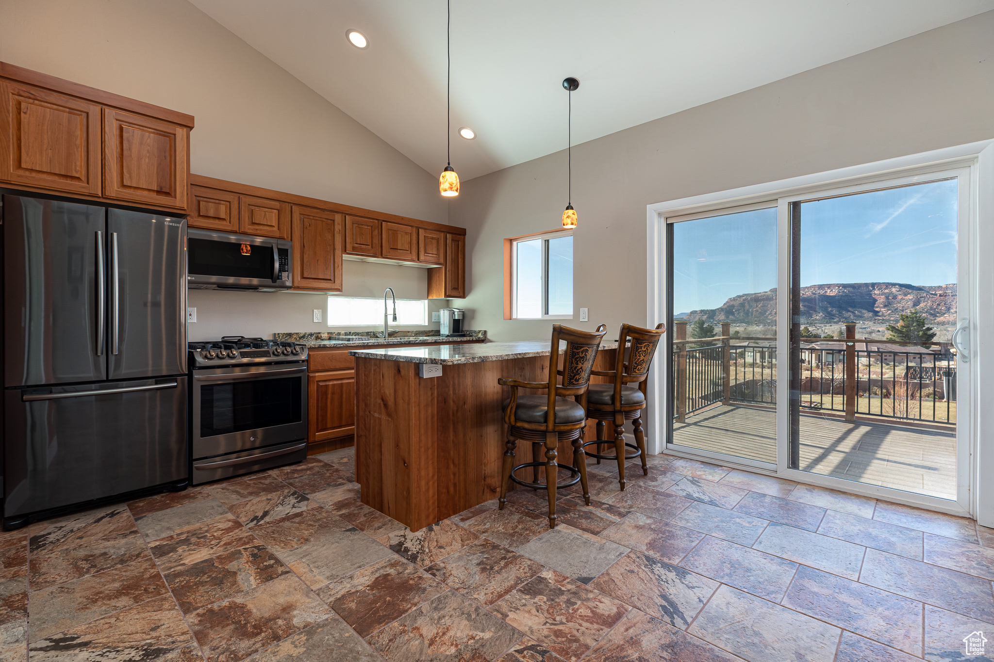 Kitchen featuring light stone countertops, a kitchen breakfast bar, high vaulted ceiling, a mountain view, and appliances with stainless steel finishes