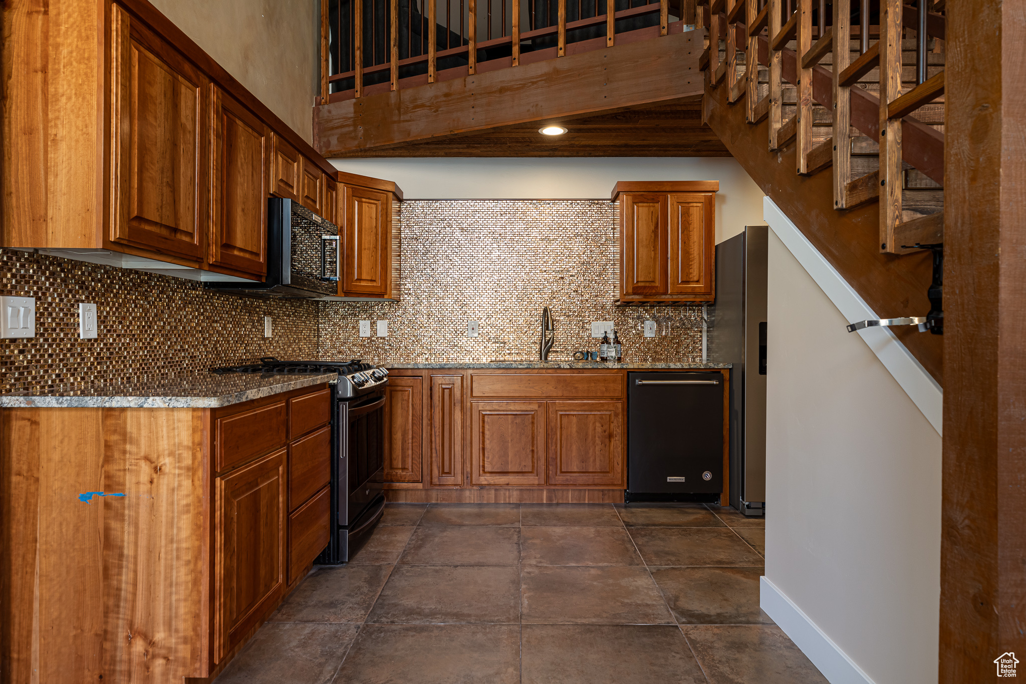 Kitchen featuring stone counters, backsplash, sink, and black appliances