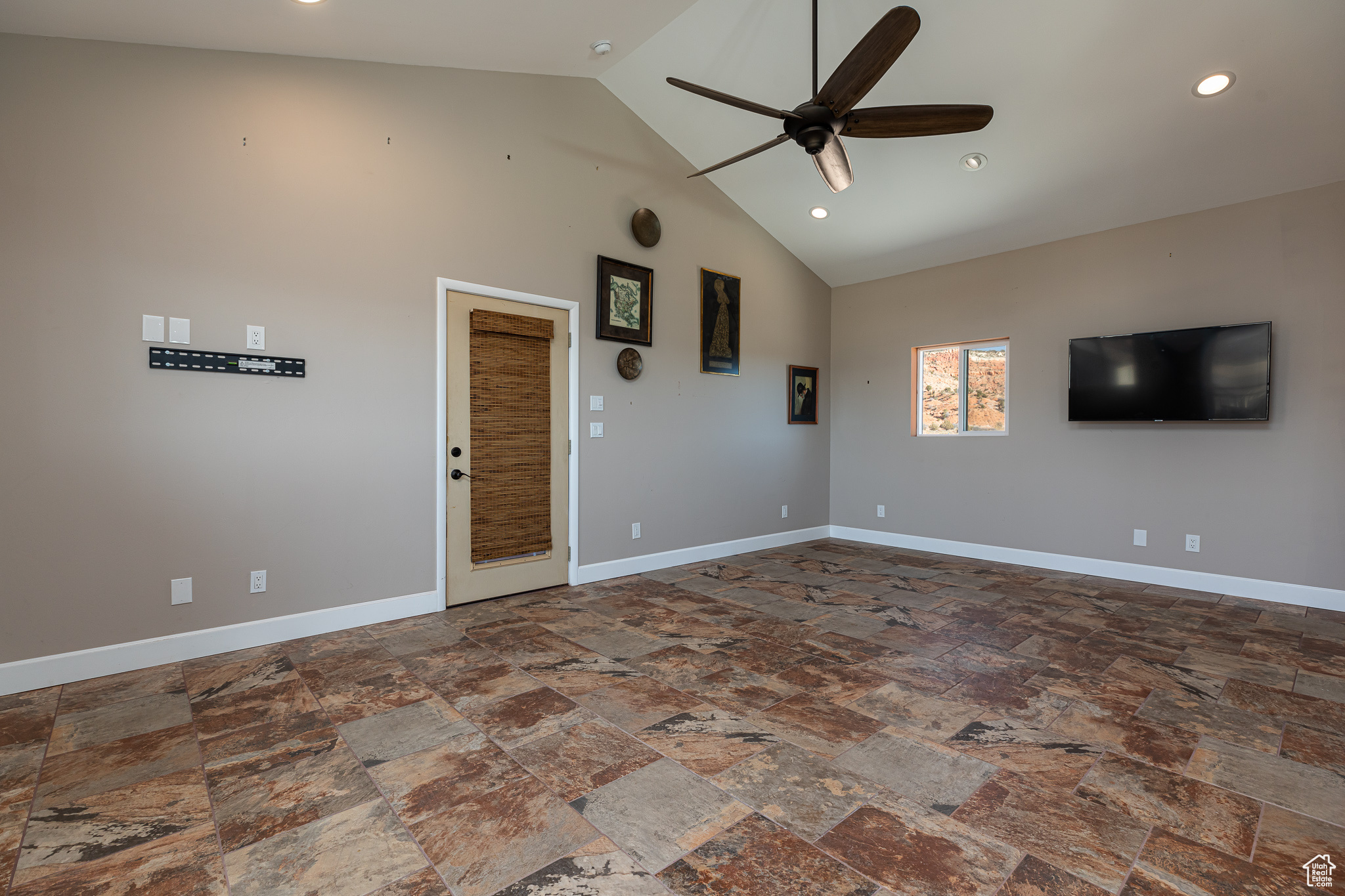 Unfurnished living room featuring ceiling fan and high vaulted ceiling