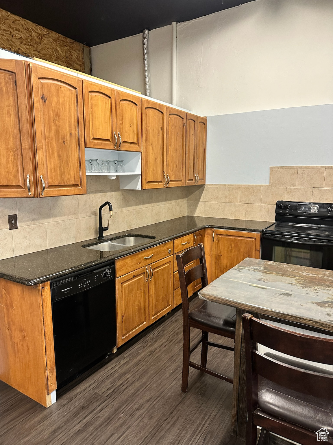 Kitchen with black appliances, decorative backsplash, sink, and dark wood-type flooring