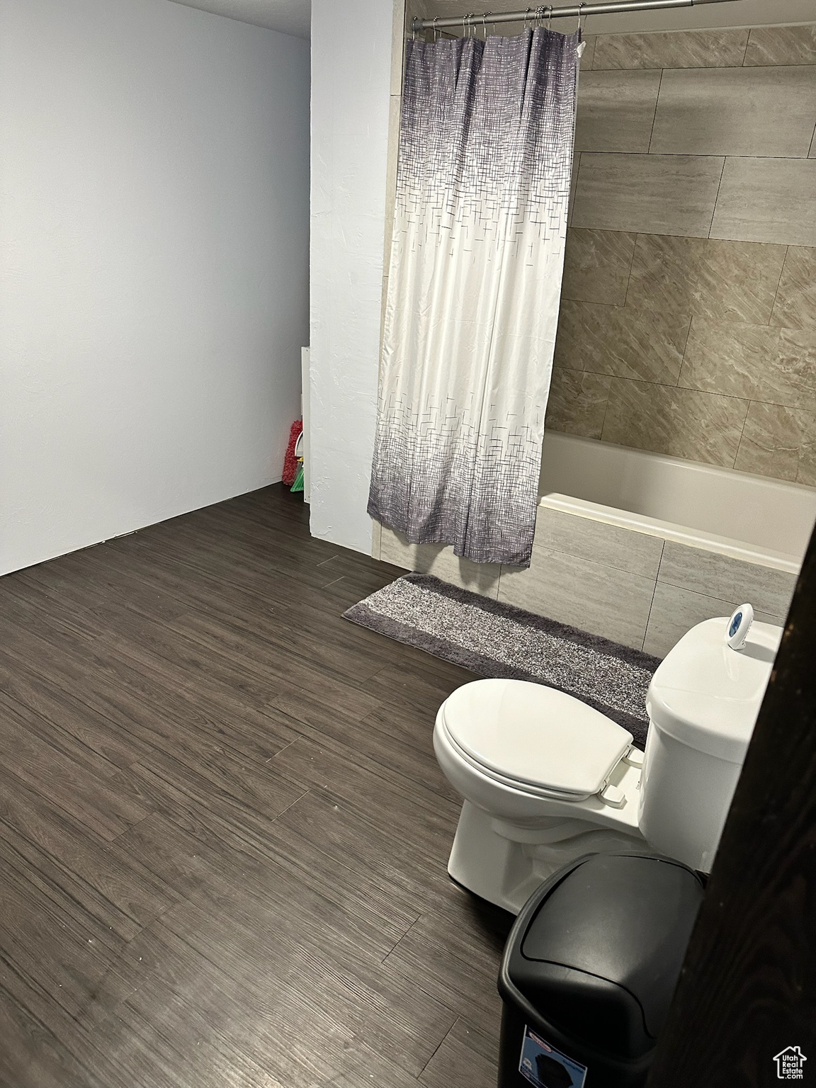 Bathroom featuring hardwood / wood-style flooring, toilet, and shower / bath combo with shower curtain