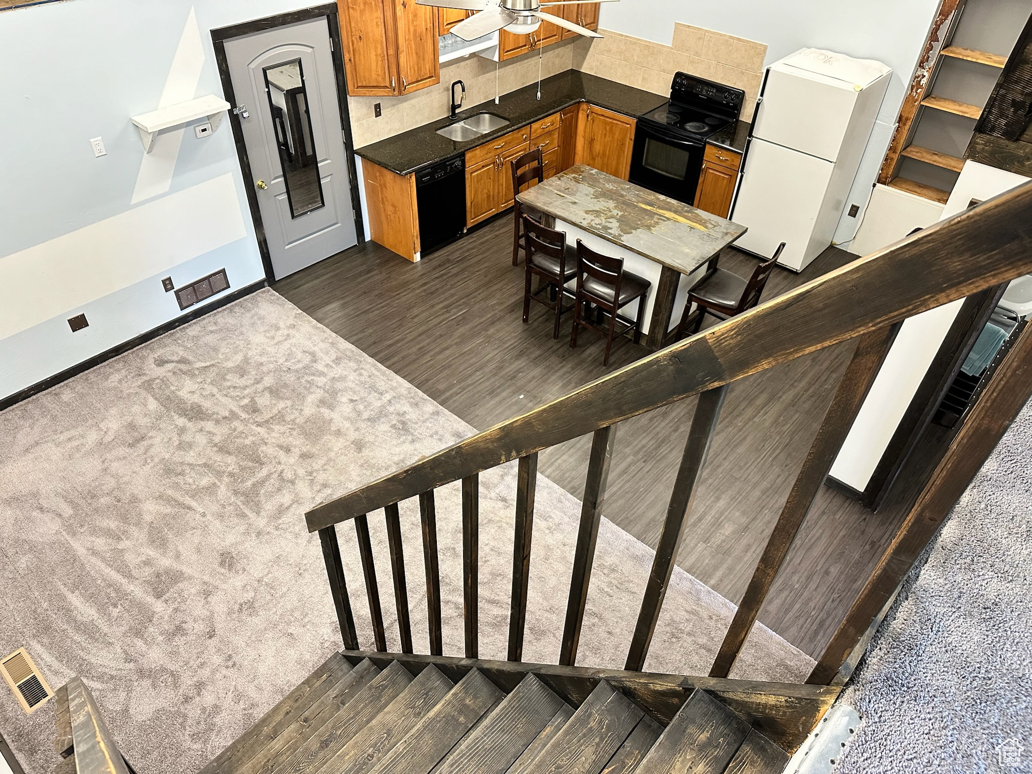 Kitchen with ceiling fan, sink, dark wood-type flooring, decorative backsplash, and black appliances