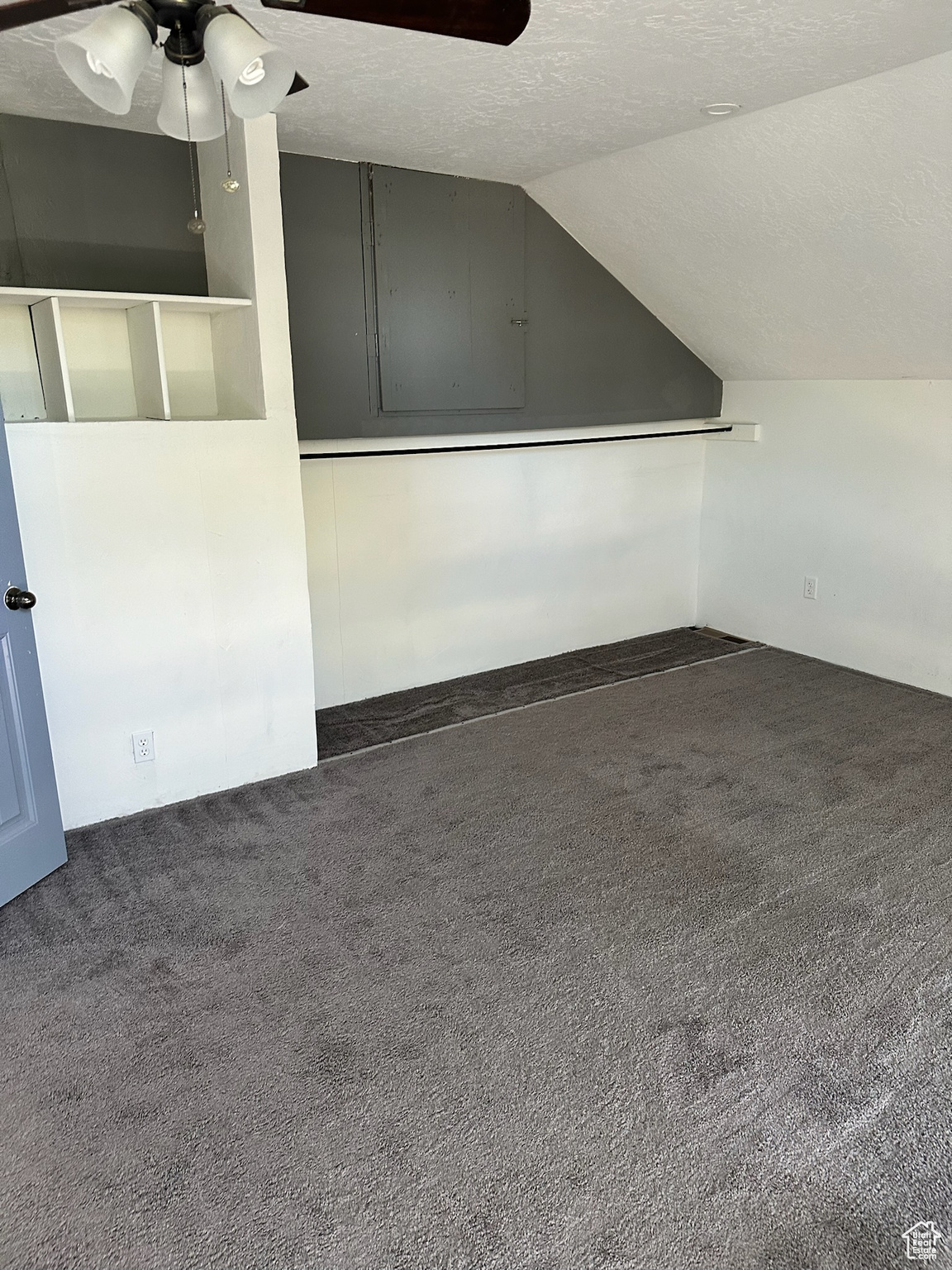 Bonus room featuring dark colored carpet, ceiling fan, a textured ceiling, and vaulted ceiling