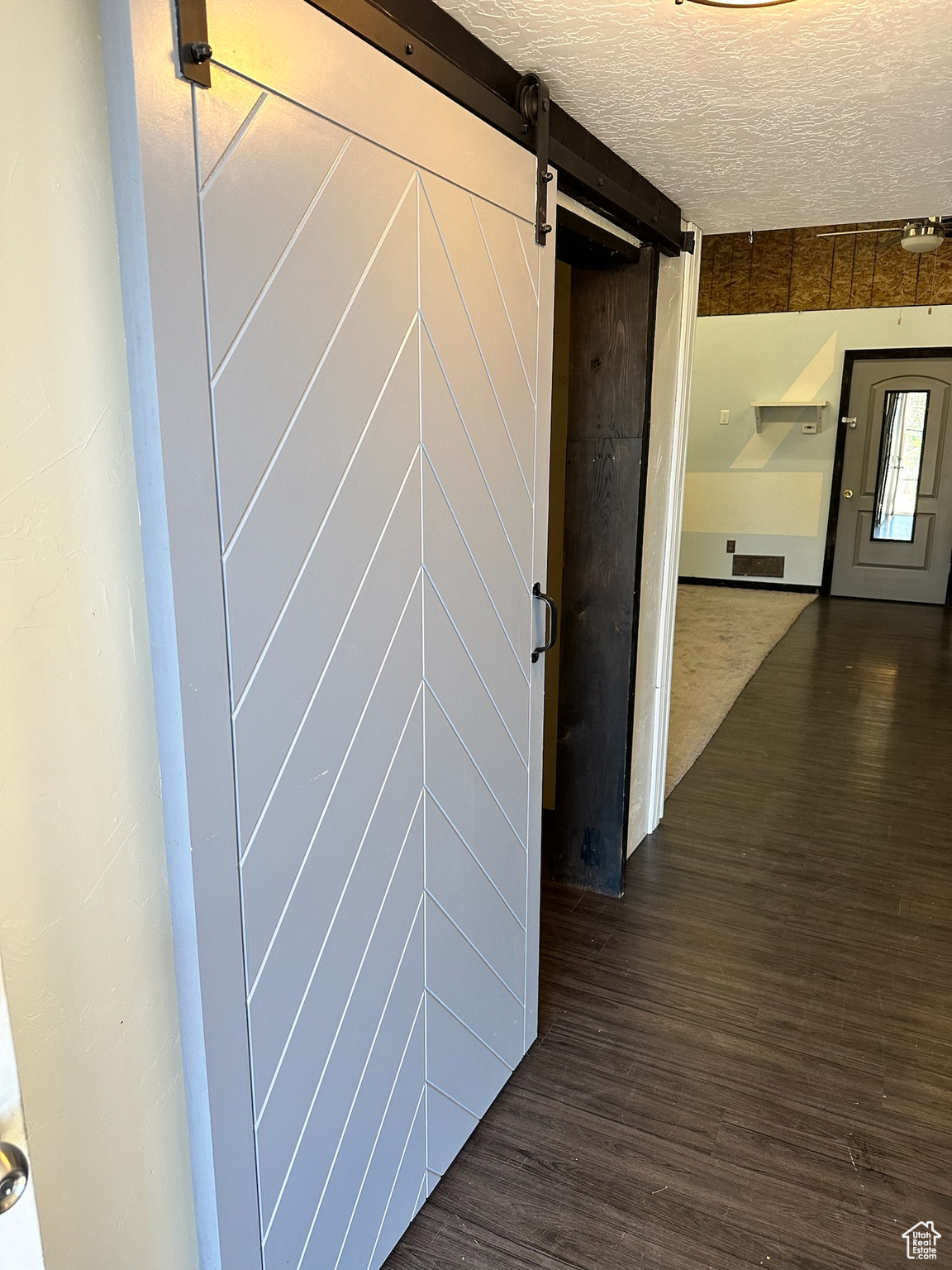 Hall with a textured ceiling, a barn door, and dark wood-type flooring