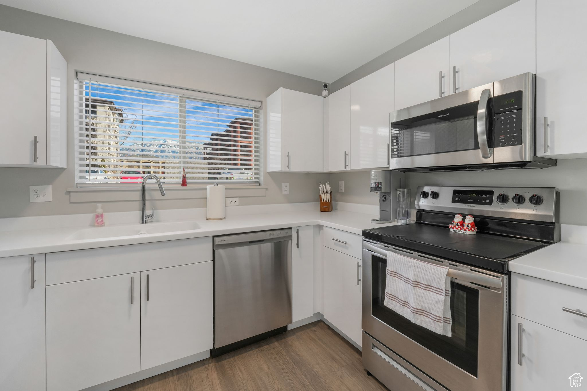 Kitchen featuring sink, white cabinets, stainless steel appliances, and dark hardwood / wood-style floors