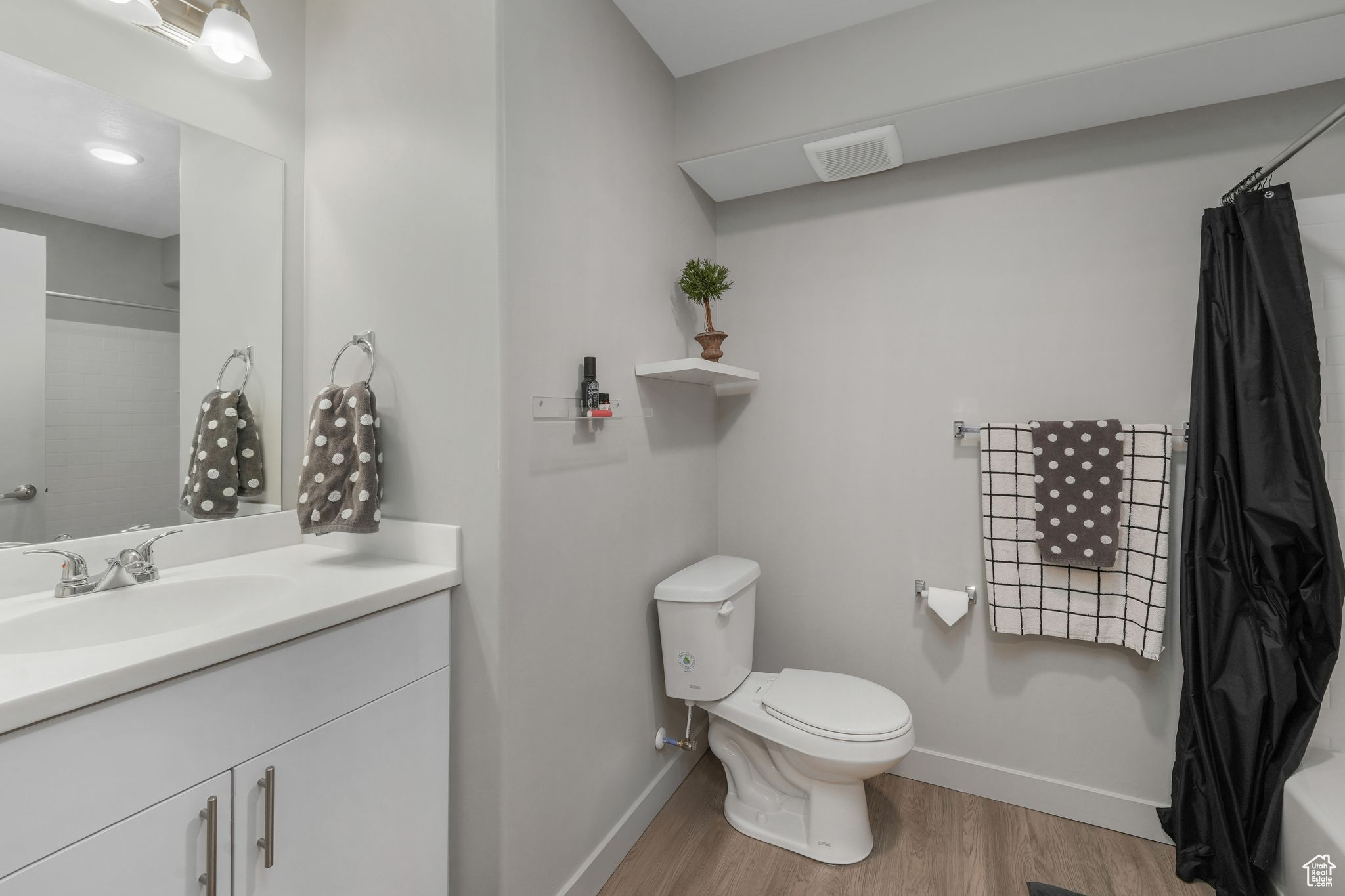 Full bathroom featuring hardwood / wood-style floors, vanity, toilet, and shower / bath combo