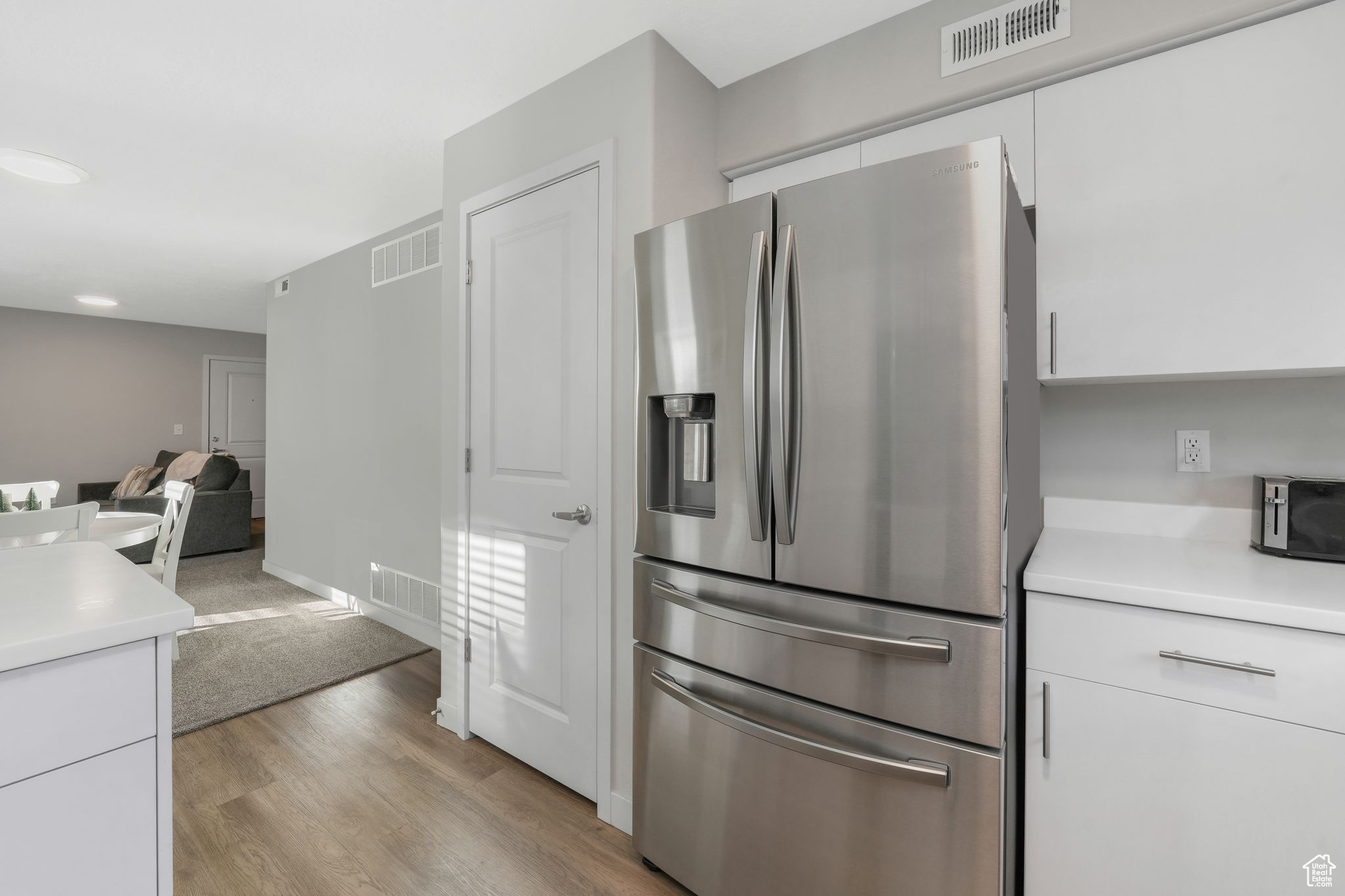 Kitchen featuring white cabinetry, stainless steel fridge, and light hardwood / wood-style flooring