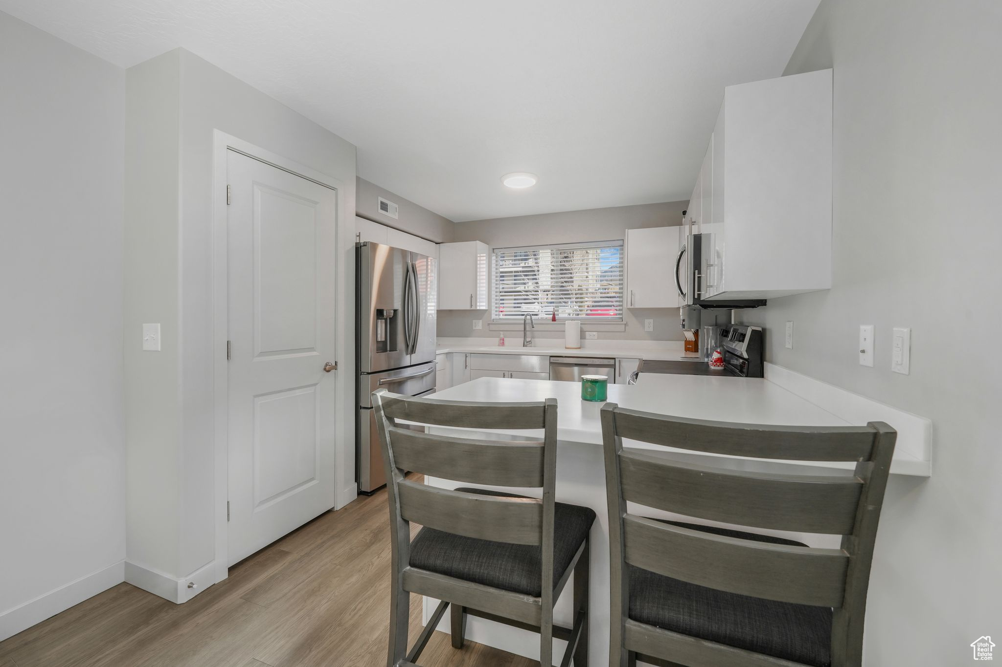 Kitchen featuring white cabinets, sink, light wood-type flooring, and stainless steel appliances