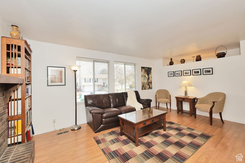 Living room with light wood-type flooring and a brick fireplace