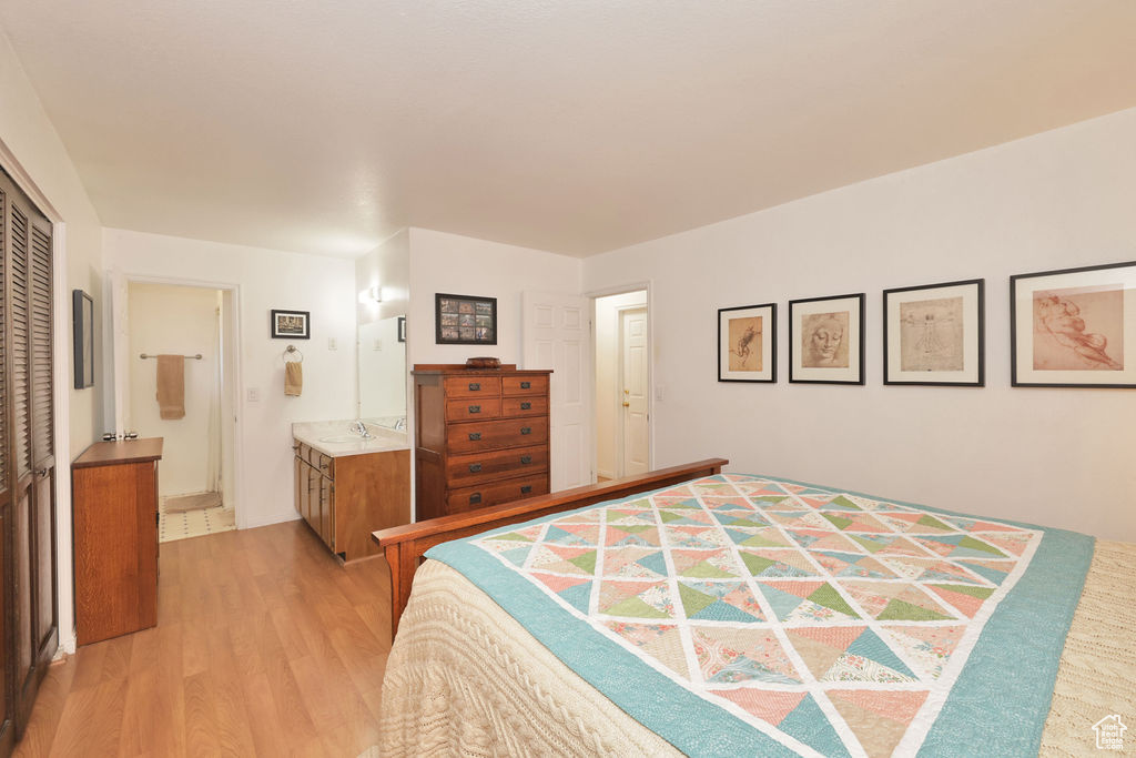 Bedroom with light wood-type flooring, ensuite bath, a closet, and sink