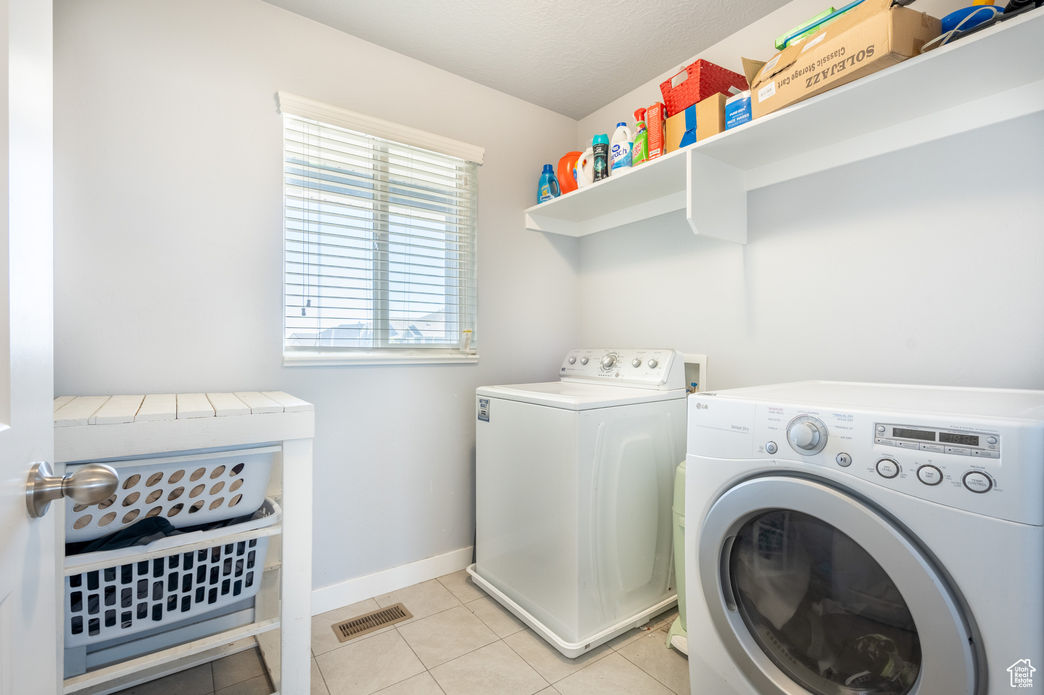 Clothes washing area with separate washer and dryer and light tile patterned floors