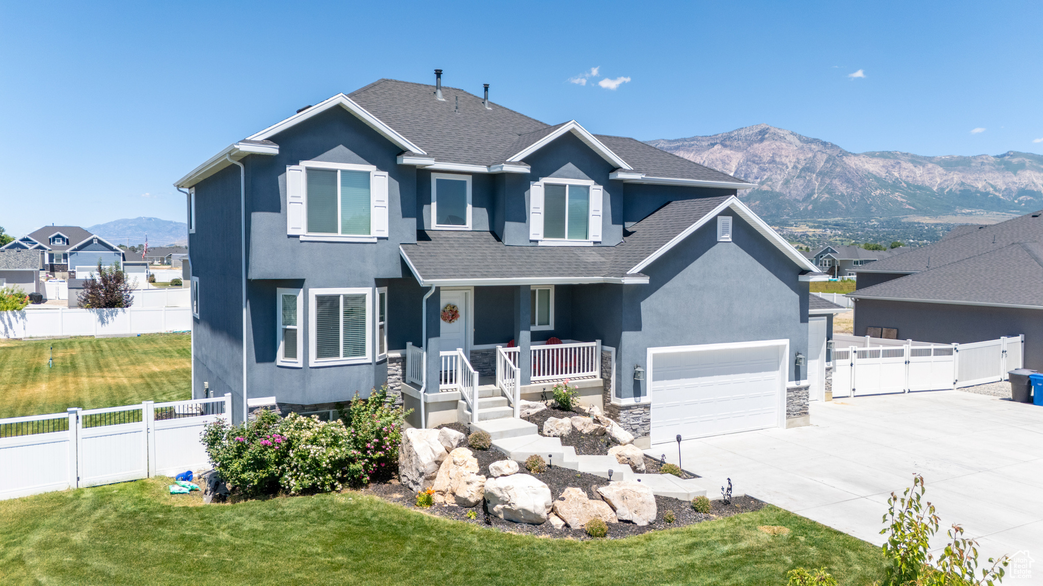 View of front of house with a mountain view, a garage, a porch, and a front yard