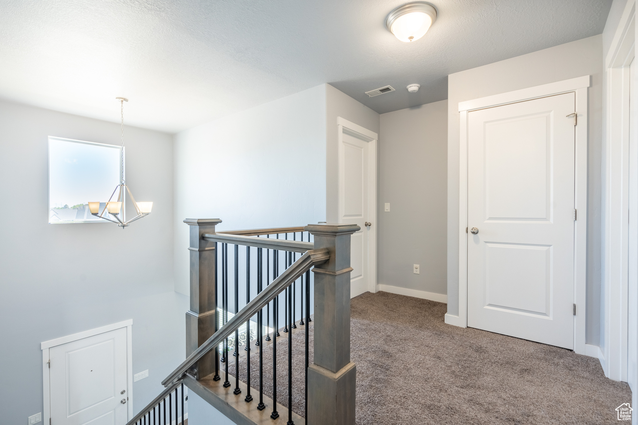 Hallway featuring carpet and a notable chandelier