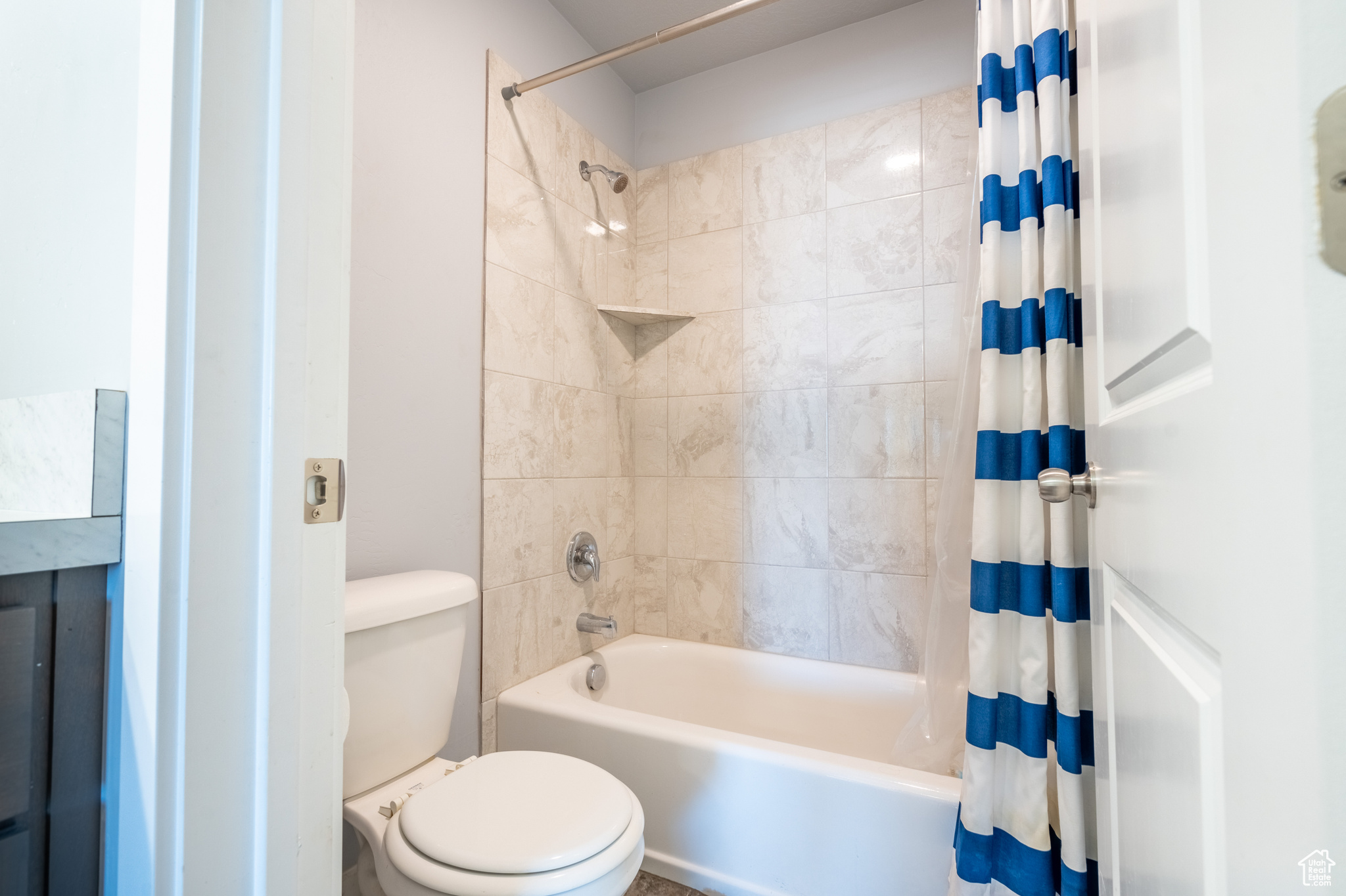 Bathroom featuring toilet and shower / tub combo with curtain