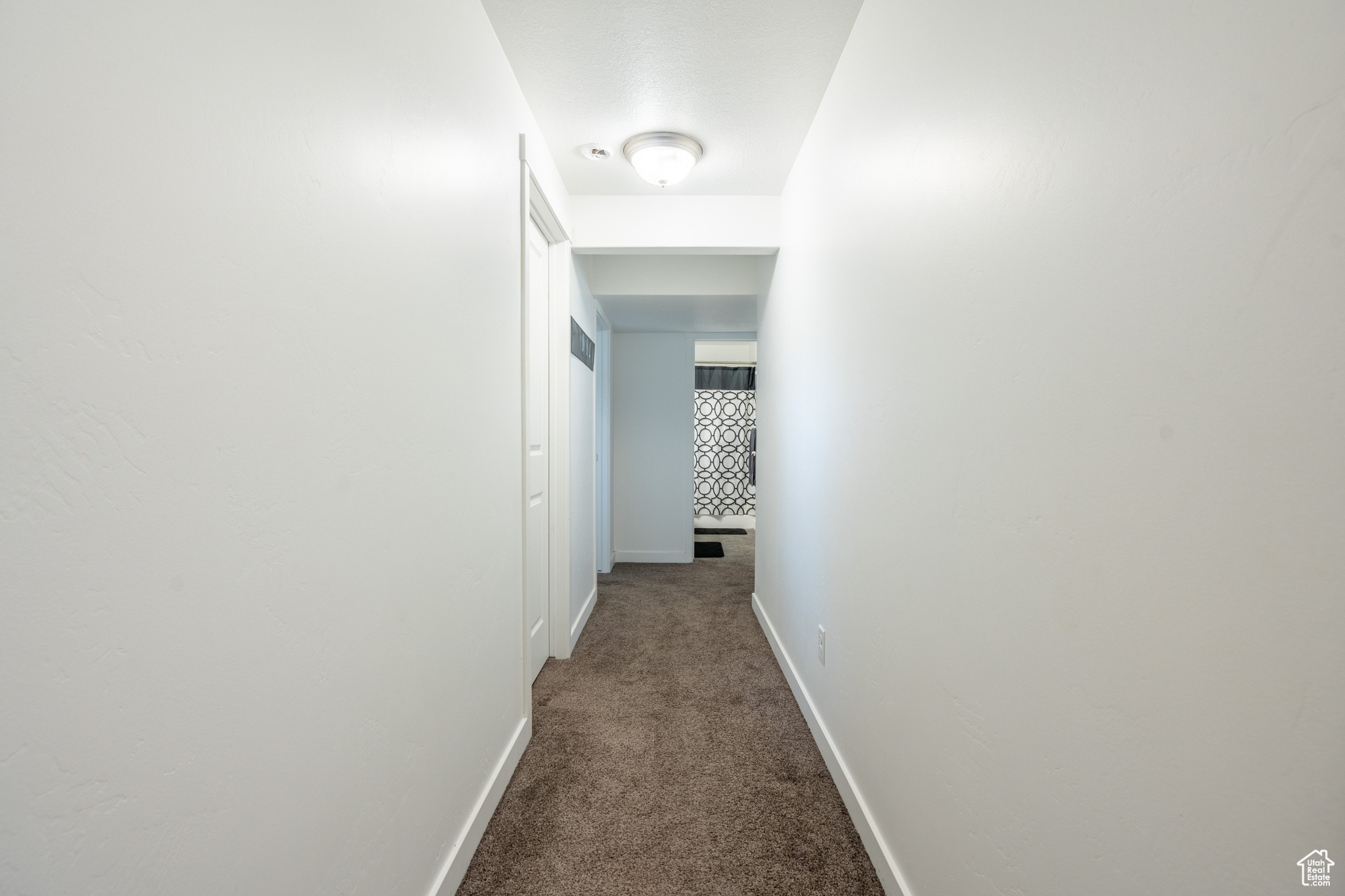 Corridor featuring dark carpet