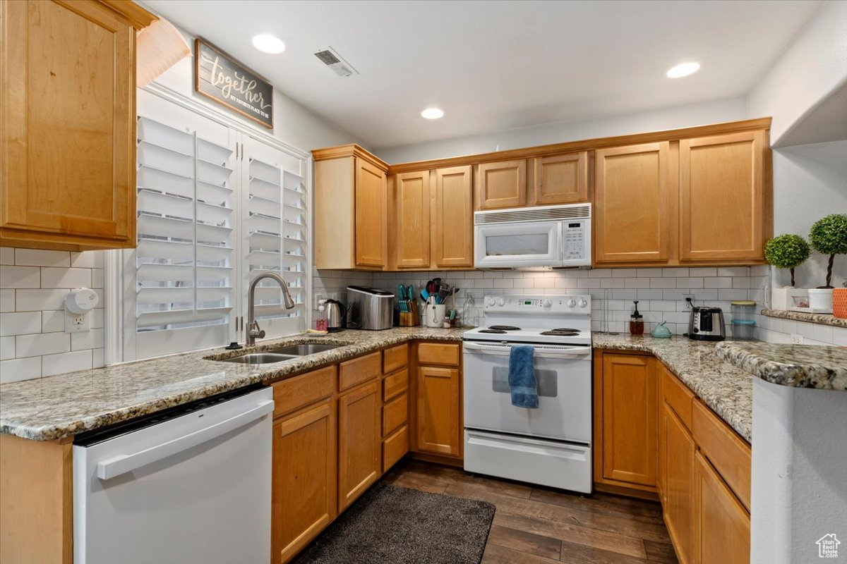 Kitchen with white appliances, tasteful backsplash, light stone counters, and sink