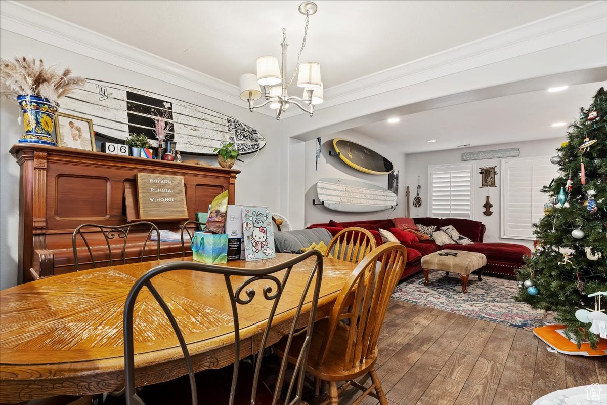 Dining area featuring a chandelier, wood-type flooring, and crown molding