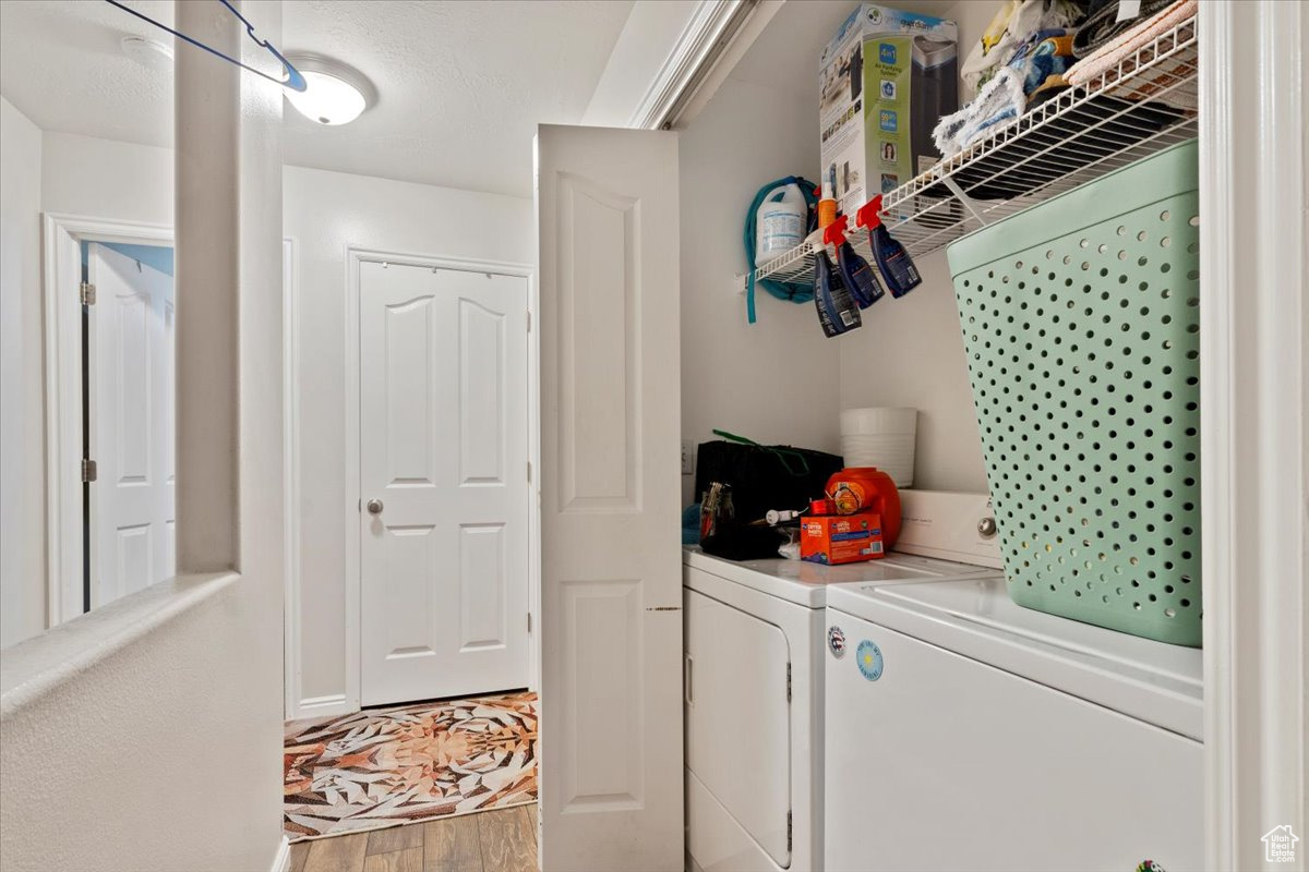 Laundry room with hardwood / wood-style floors and separate washer and dryer