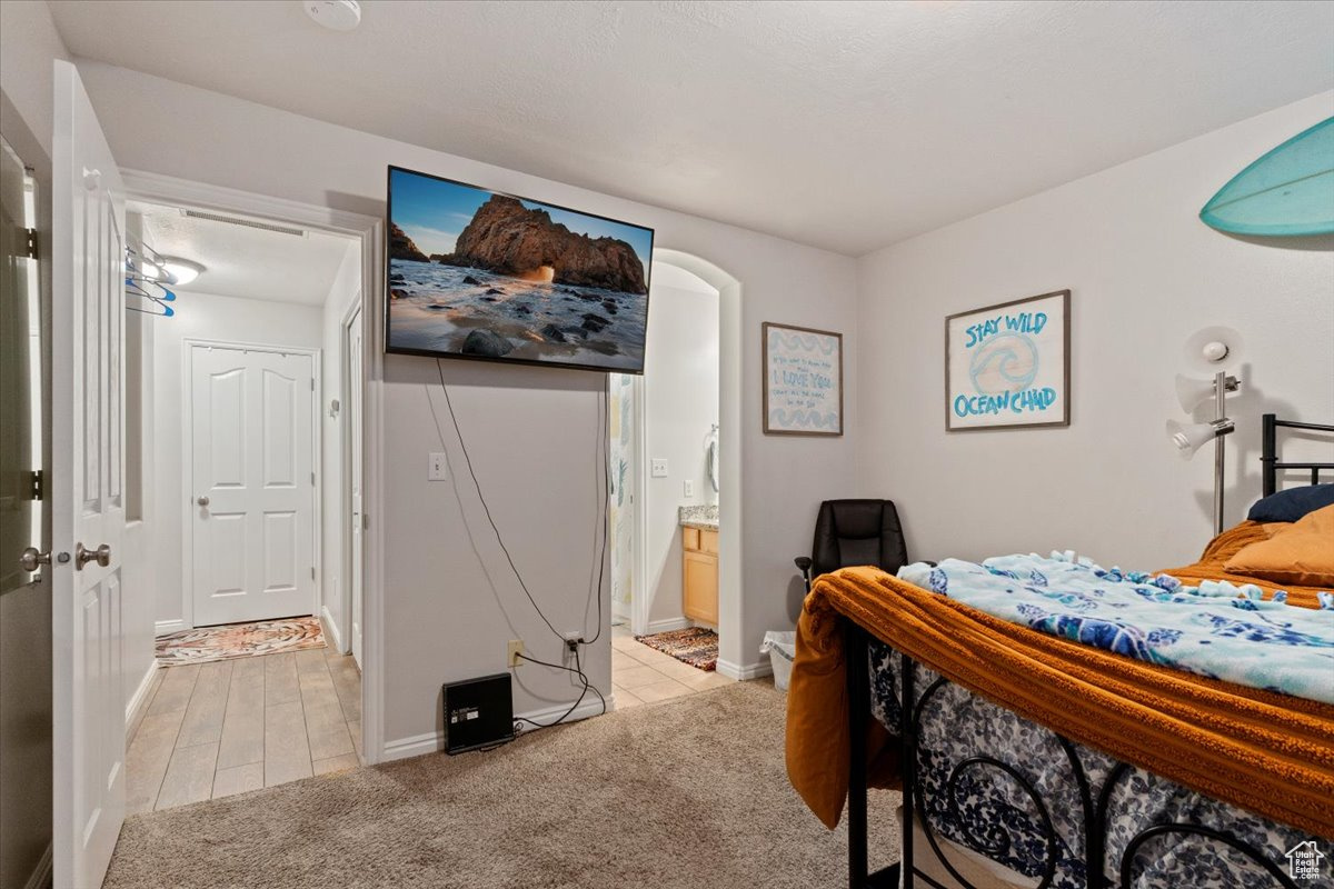 Bedroom featuring light carpet and ensuite bathroom