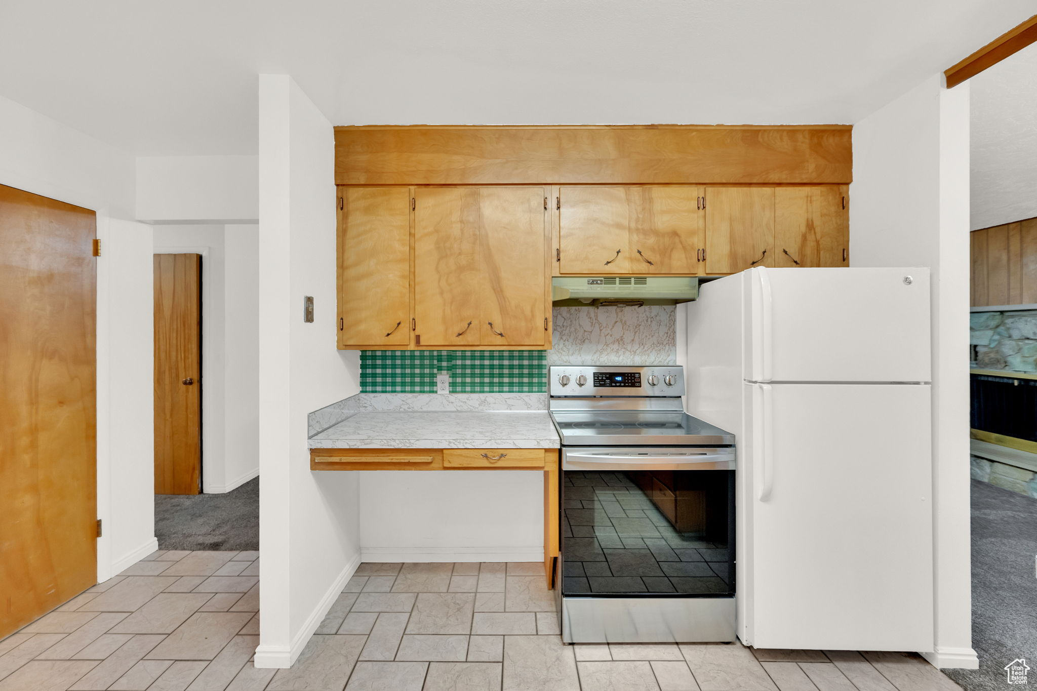 Kitchen featuring white refrigerator, tasteful backsplash, tile counters, and electric stove