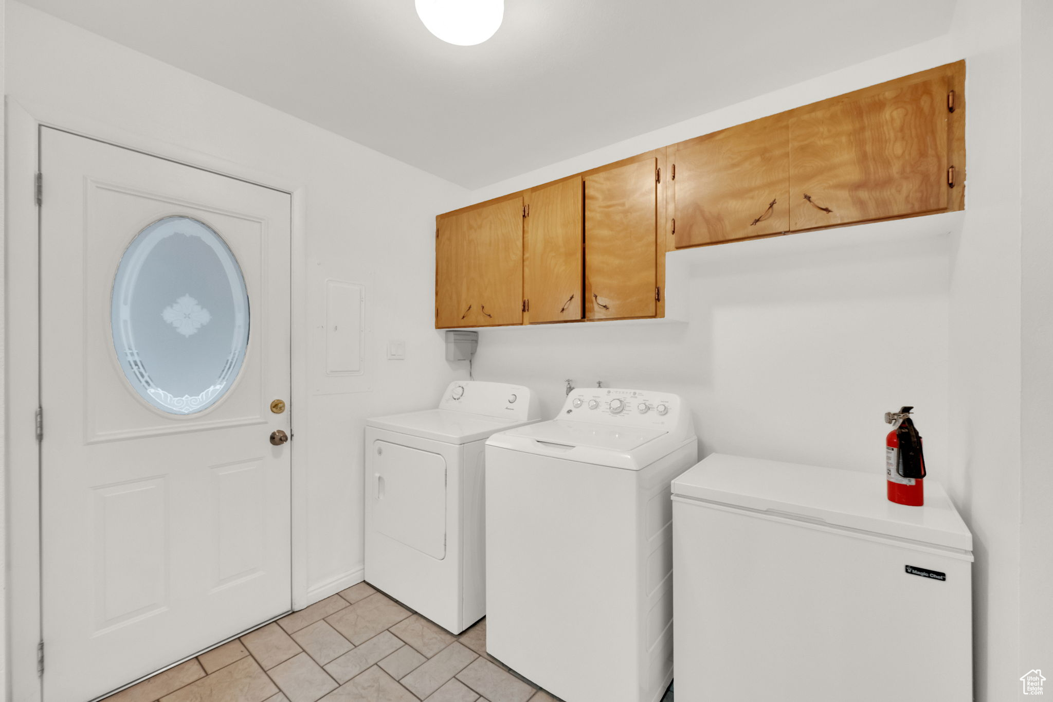 Laundry room featuring cabinets, light tile patterned floors, and washer and clothes dryer