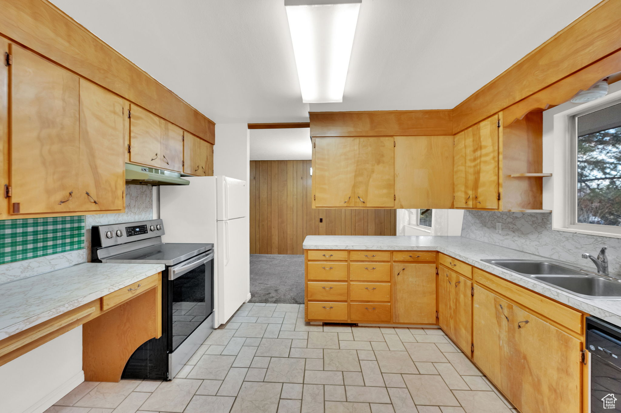 Kitchen with electric range, sink, black dishwasher, tasteful backsplash, and white fridge