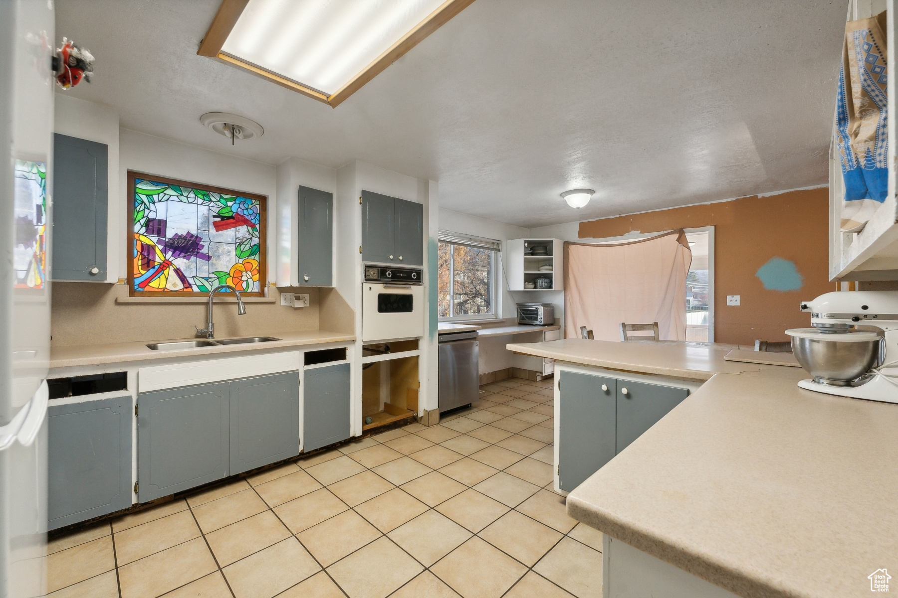 Kitchen featuring gray cabinetry, oven, light tile patterned floors, and sink