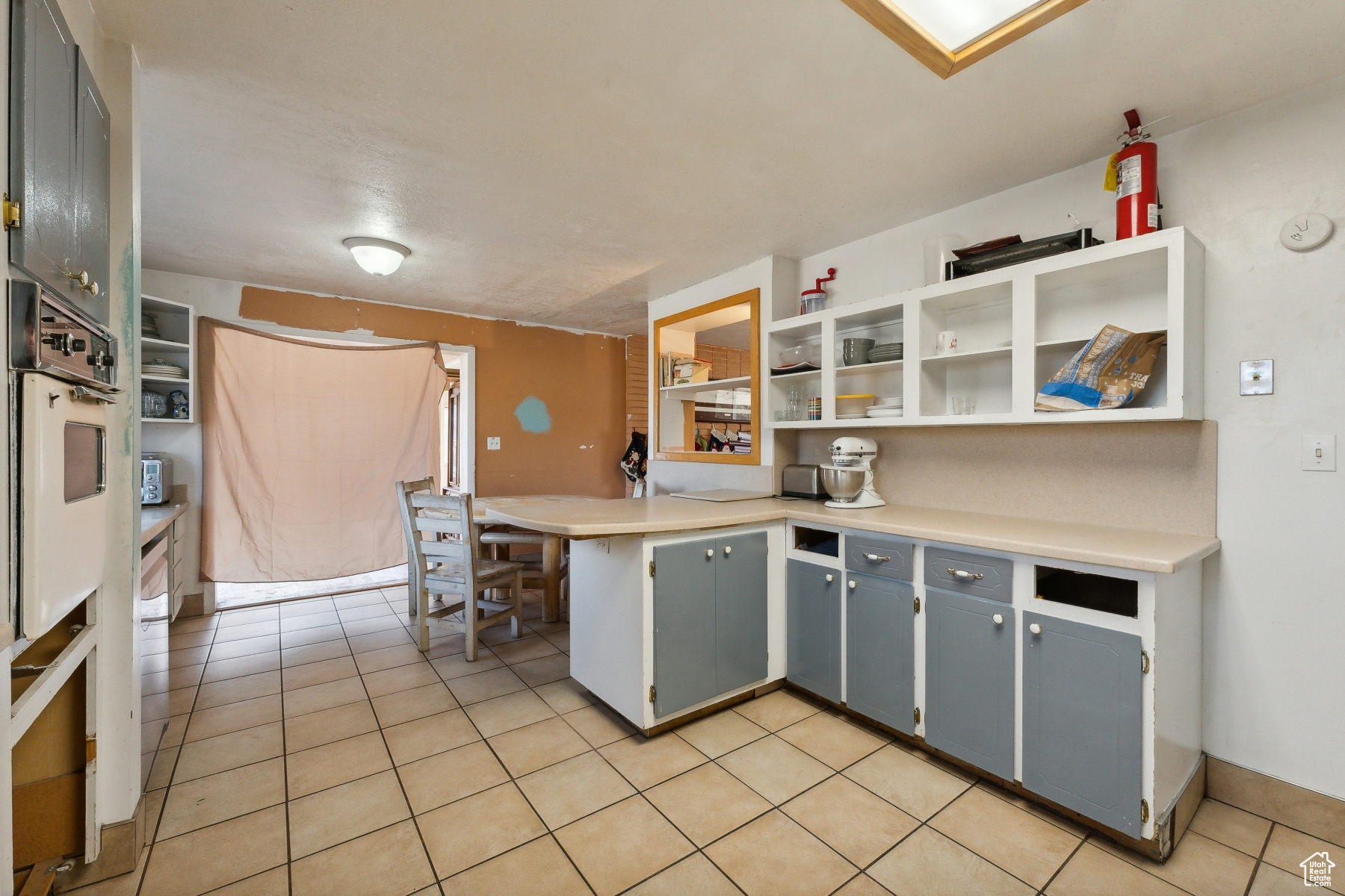 Kitchen with oven, gray cabinets, light tile patterned floors, a kitchen bar, and kitchen peninsula