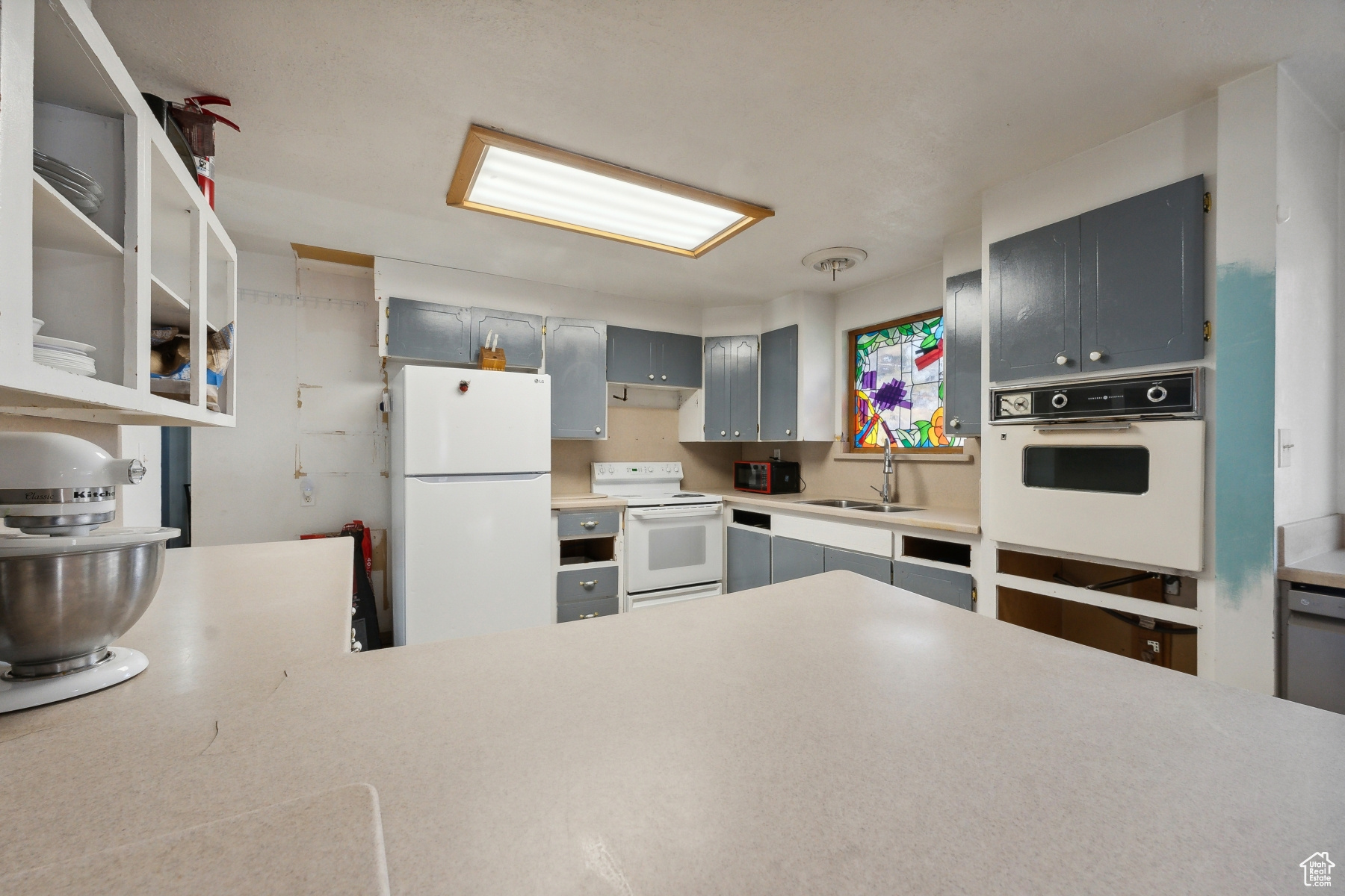 Kitchen featuring gray cabinets, sink, and white appliances