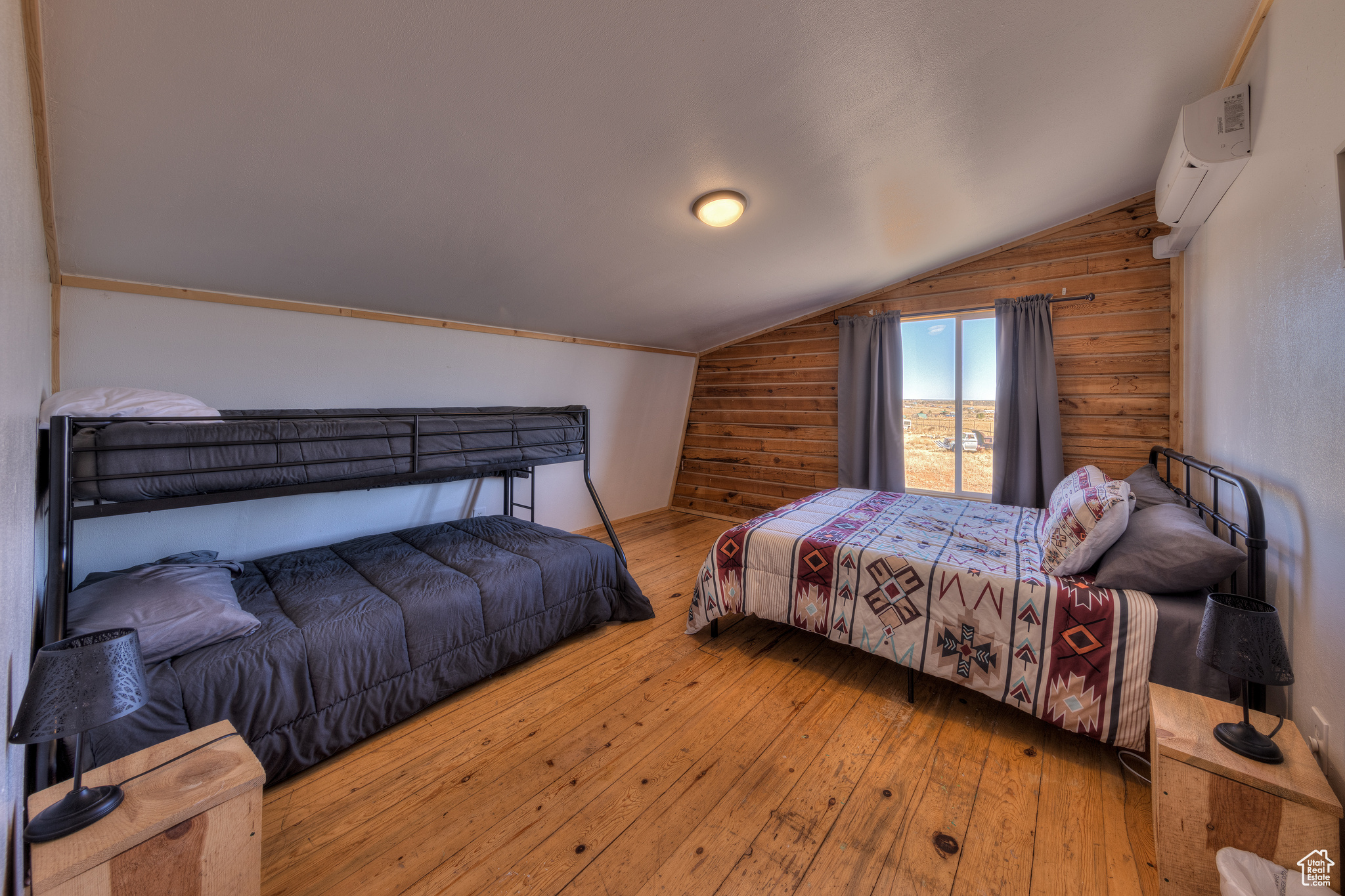 Bedroom with an AC wall unit, wooden walls, wood-type flooring, and vaulted ceiling