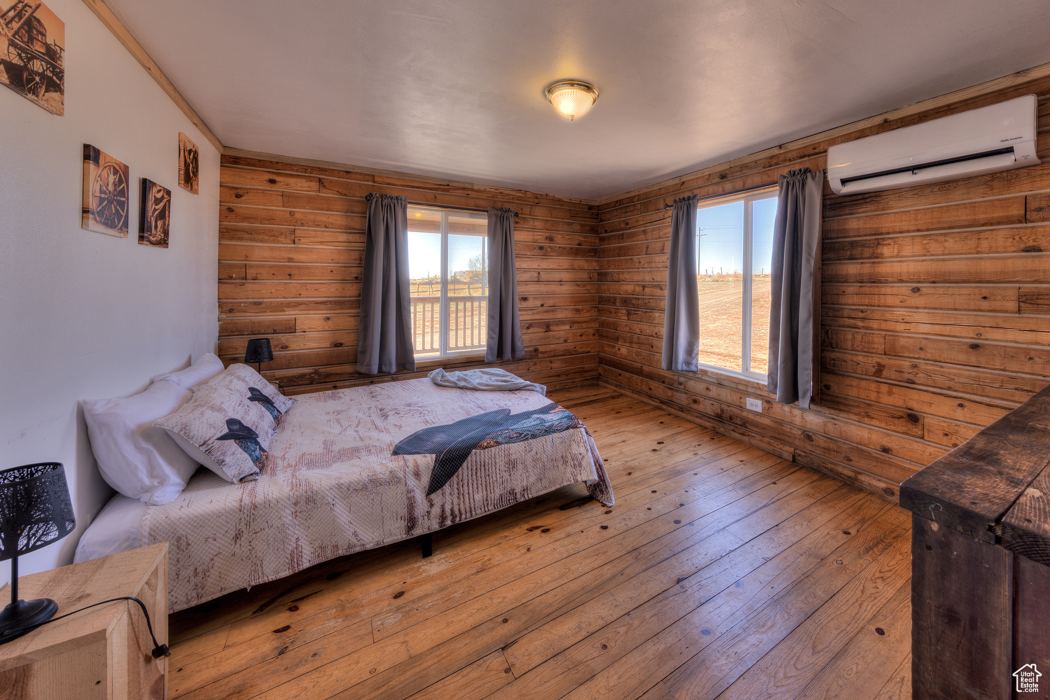 Bedroom featuring an AC wall unit, wooden walls, and light hardwood / wood-style floors