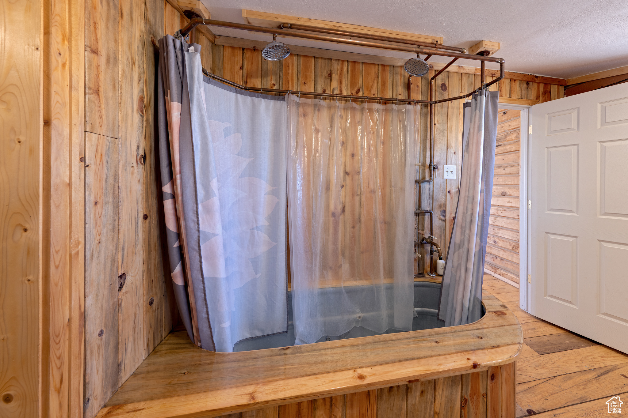 Bathroom featuring curtained shower, wood walls, and hardwood / wood-style flooring