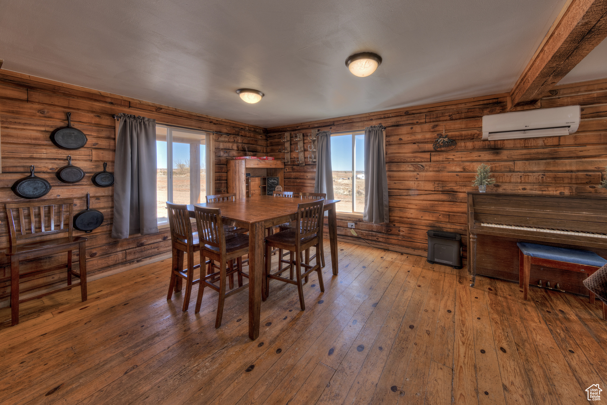 Dining room with a wall unit AC, a wealth of natural light, hardwood / wood-style floors, and wooden walls