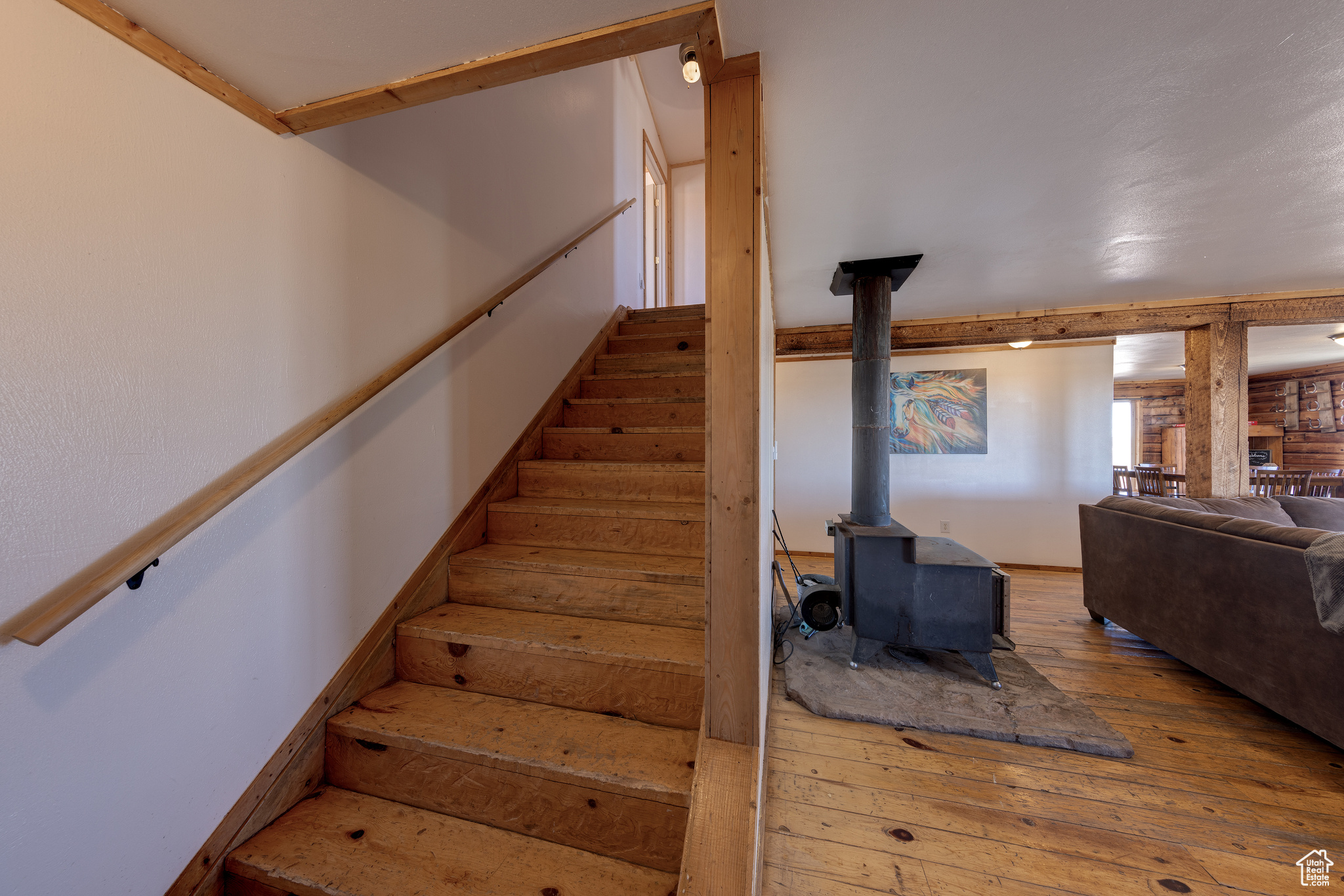 Stairway featuring wood-type flooring and a wood stove