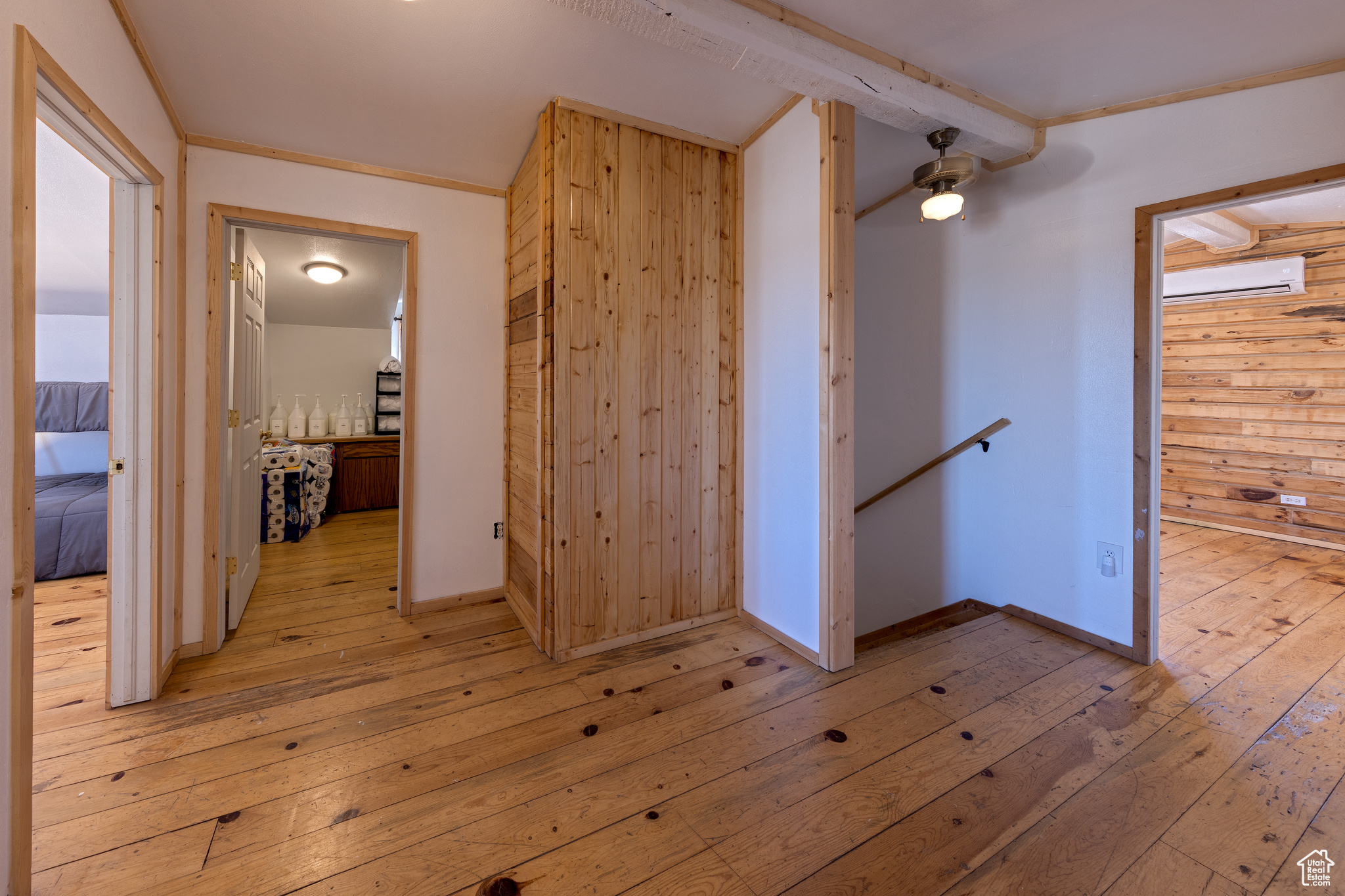 Corridor featuring wooden walls, light hardwood / wood-style floors, a wall mounted AC, and ornamental molding