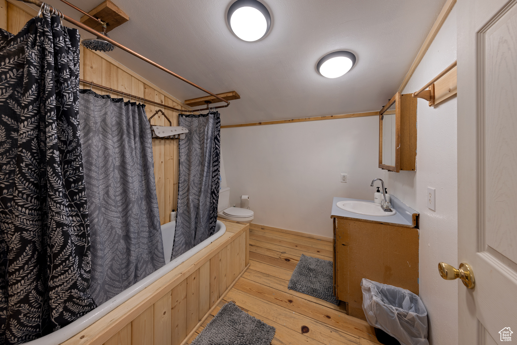 Full bathroom featuring hardwood / wood-style floors, vanity, shower / bath combo, and toilet