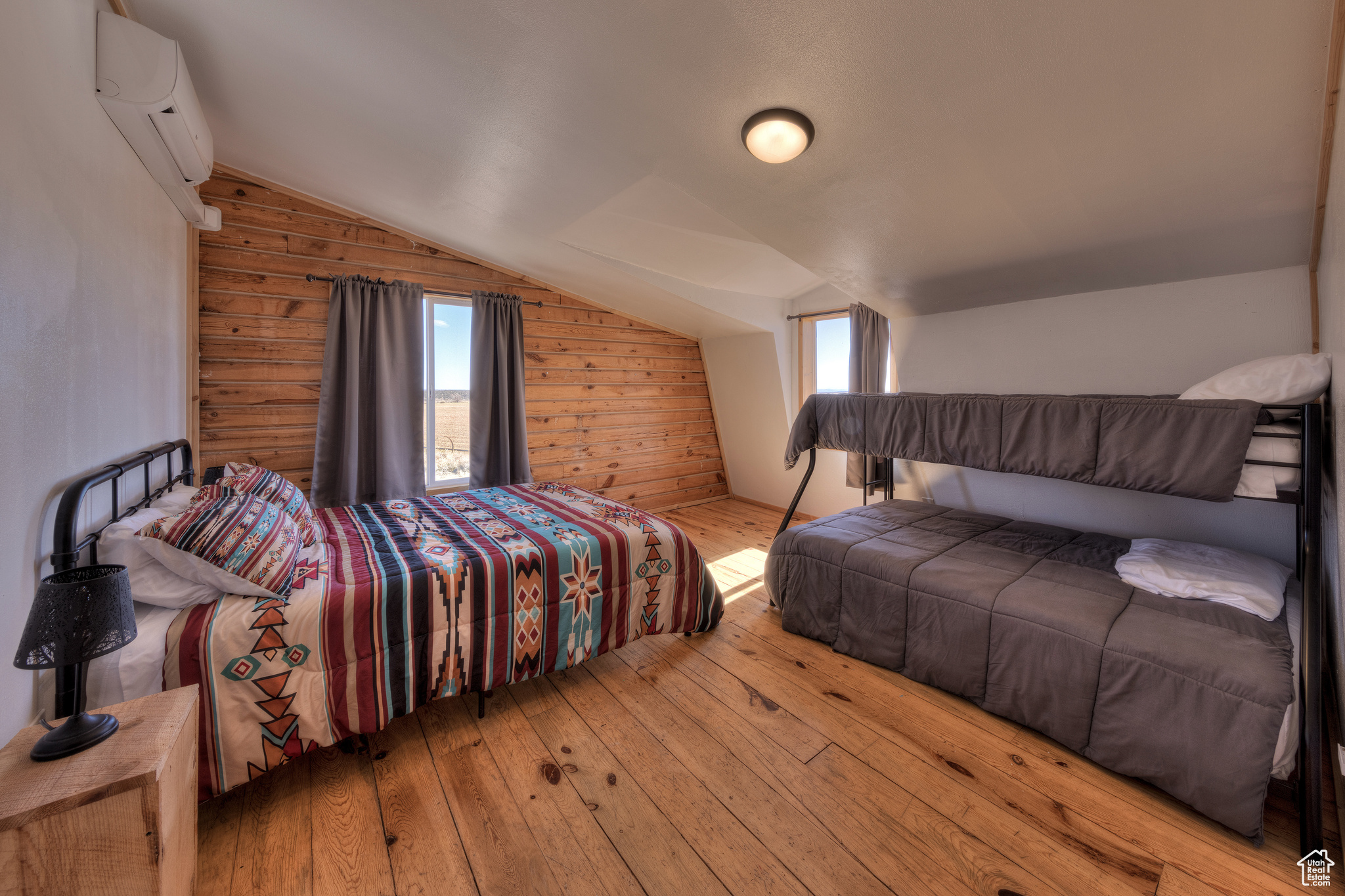 Bedroom featuring light wood-type flooring, vaulted ceiling, an AC wall unit, and wooden walls