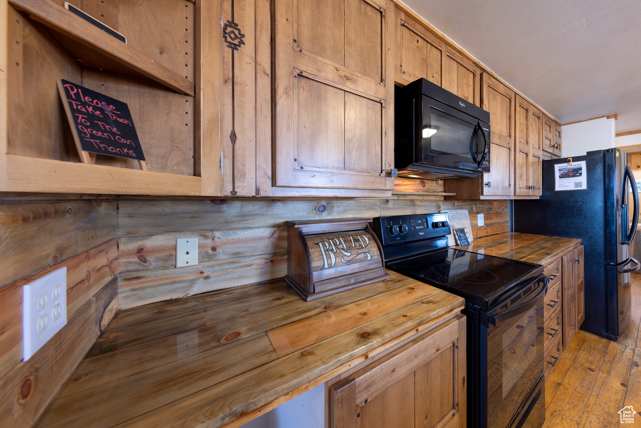 Kitchen with black appliances, wood counters, and light hardwood / wood-style floors